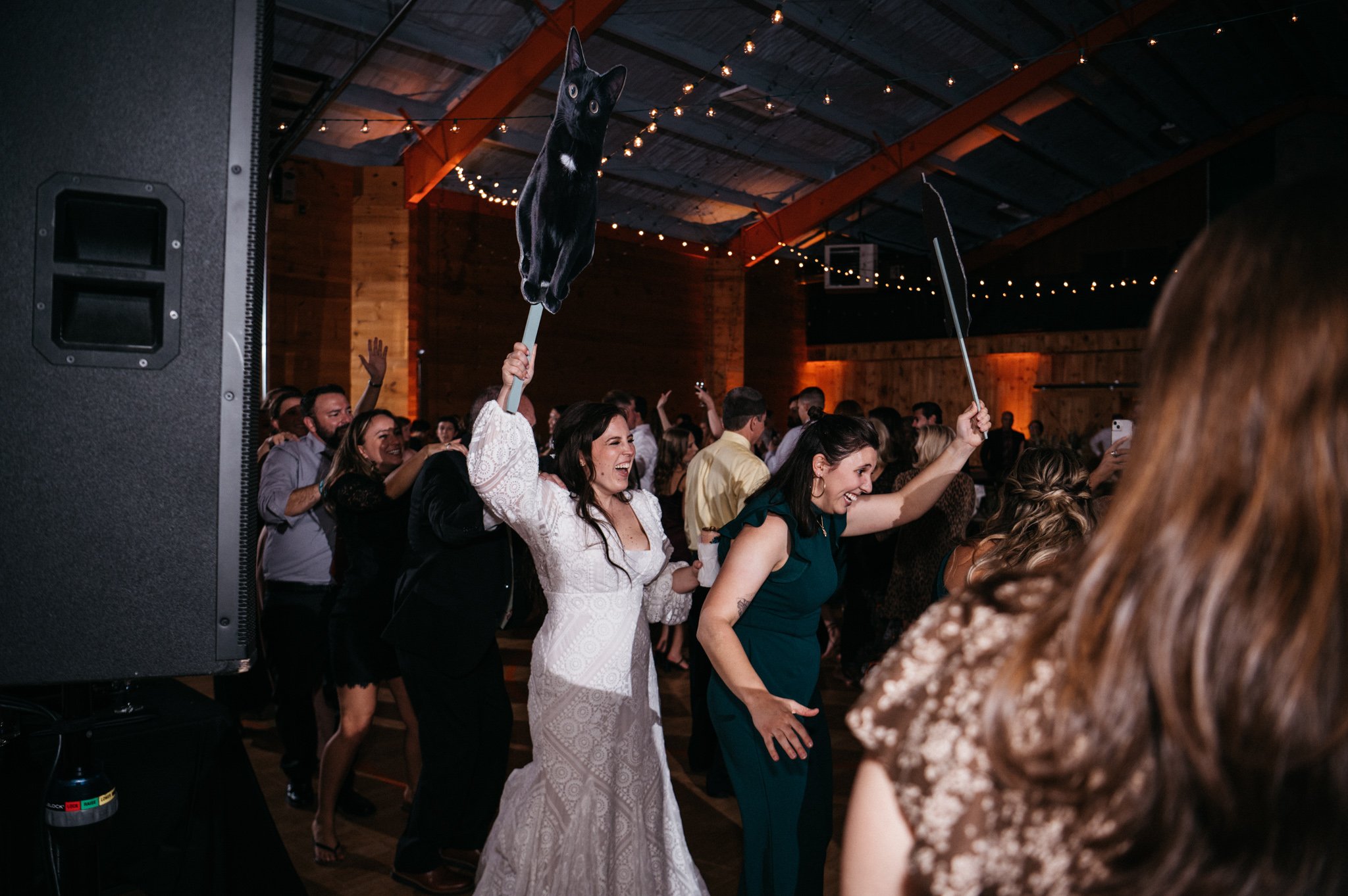 A bride holds a cardboard cutout of her cat at a wedding reception.