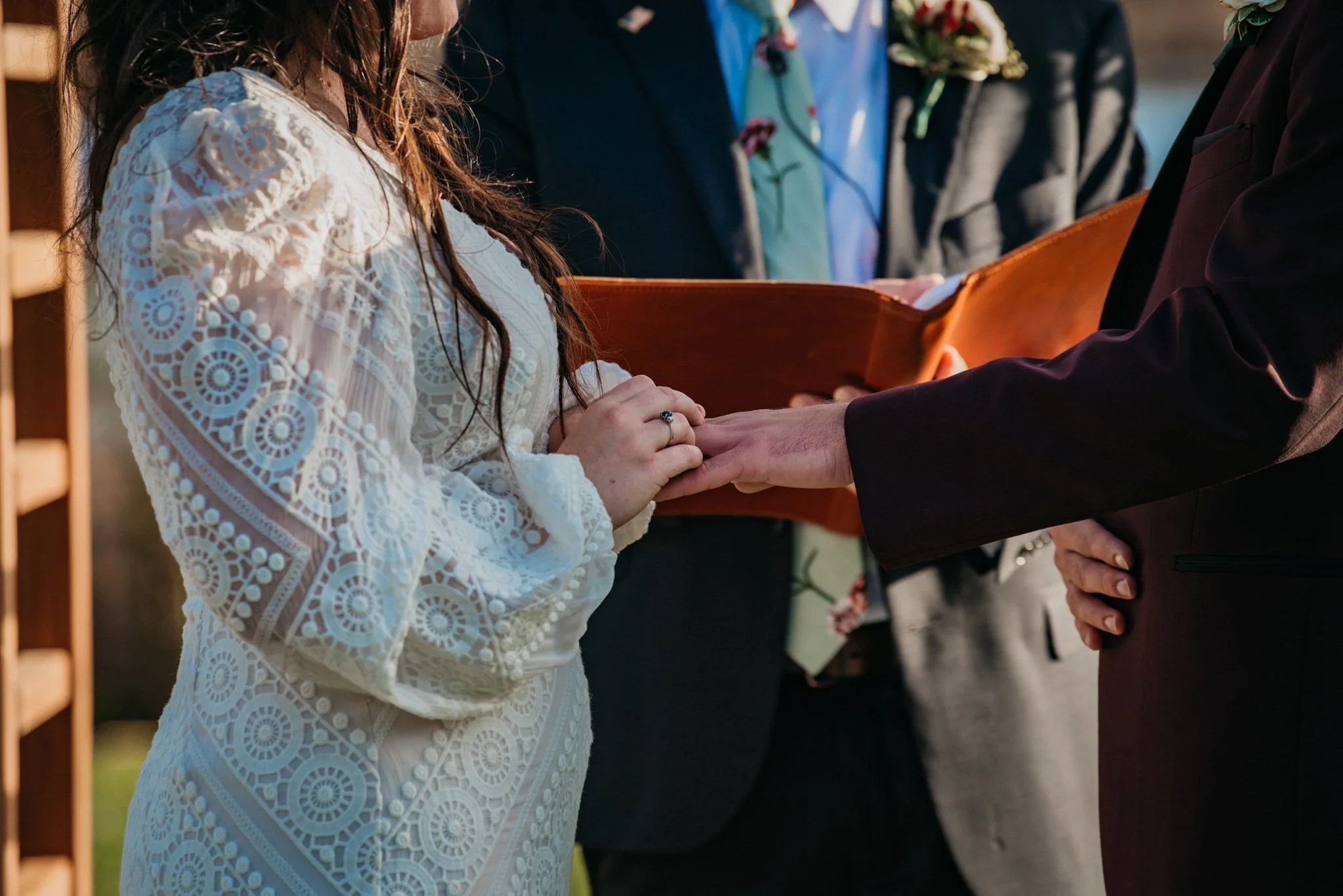 A bride puts a ring on her husbands hand.