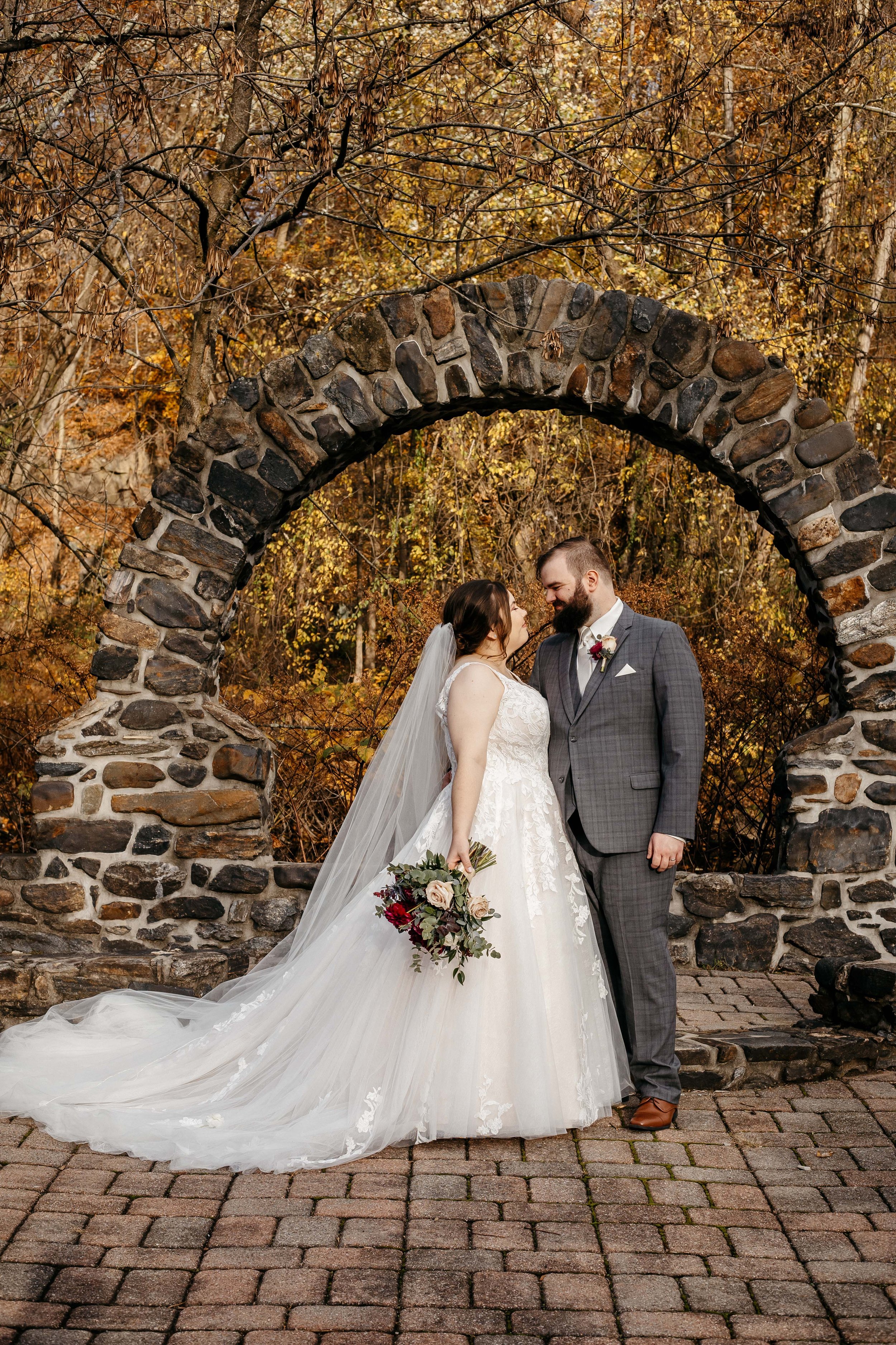 A bride and groom under a stone arch at Kings Mill.