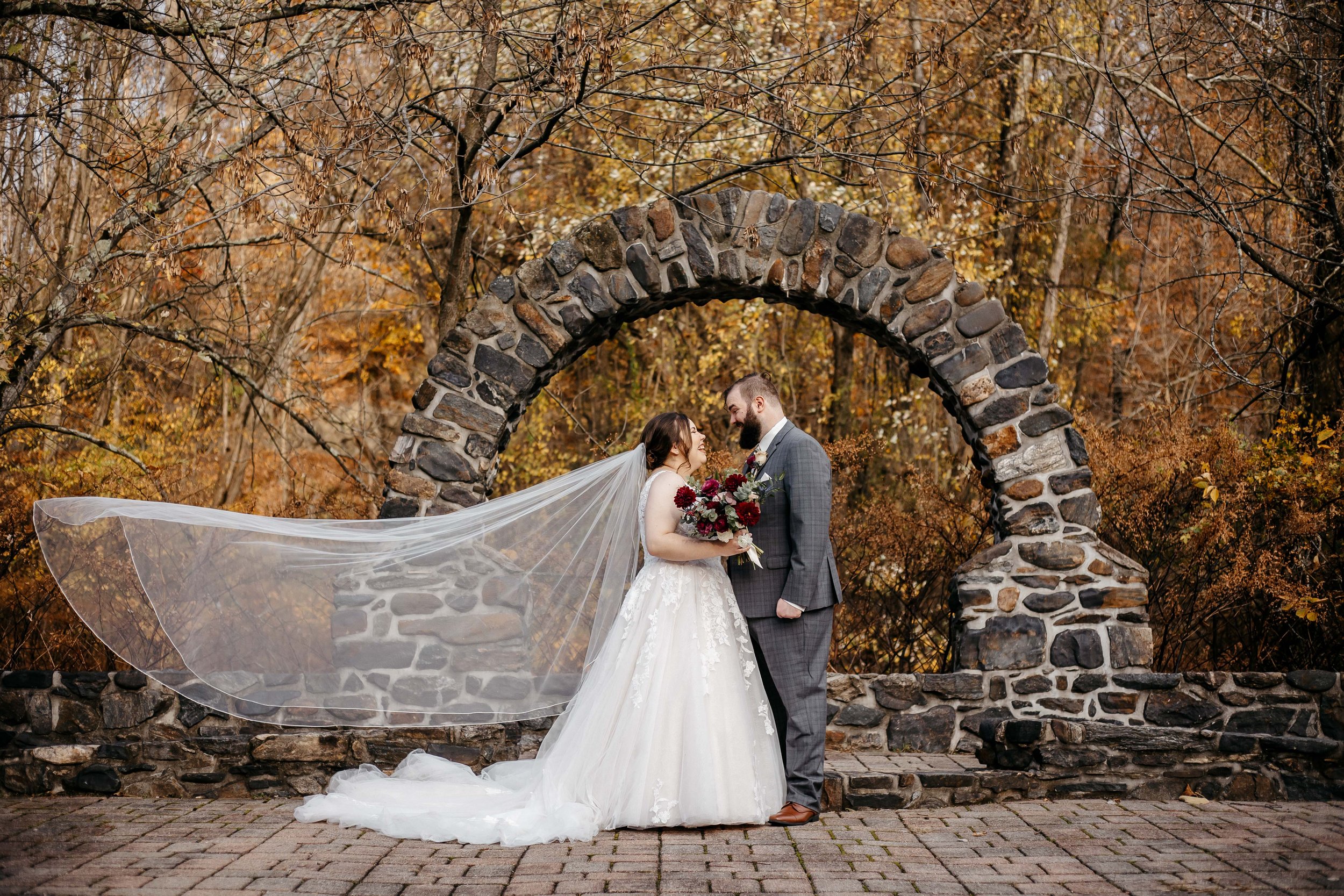 A bride and her long cathedral veil with her groom at Kings Mill.