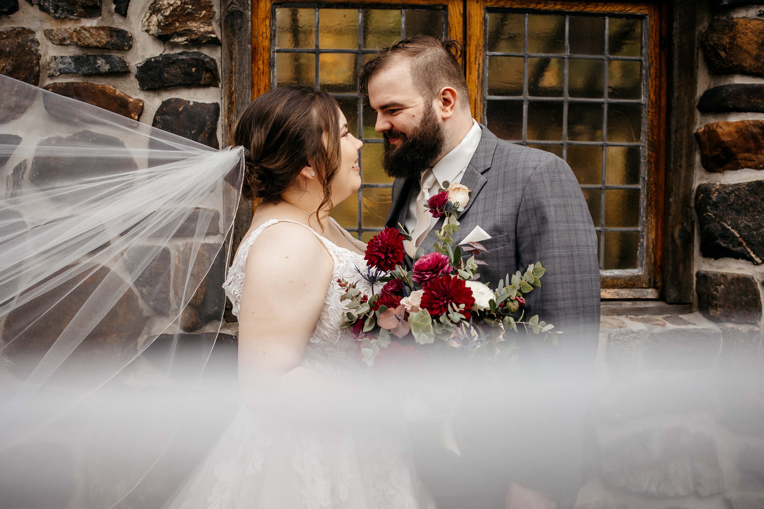 A bride and groom outside kings mill with a veil coming toward the camera.
