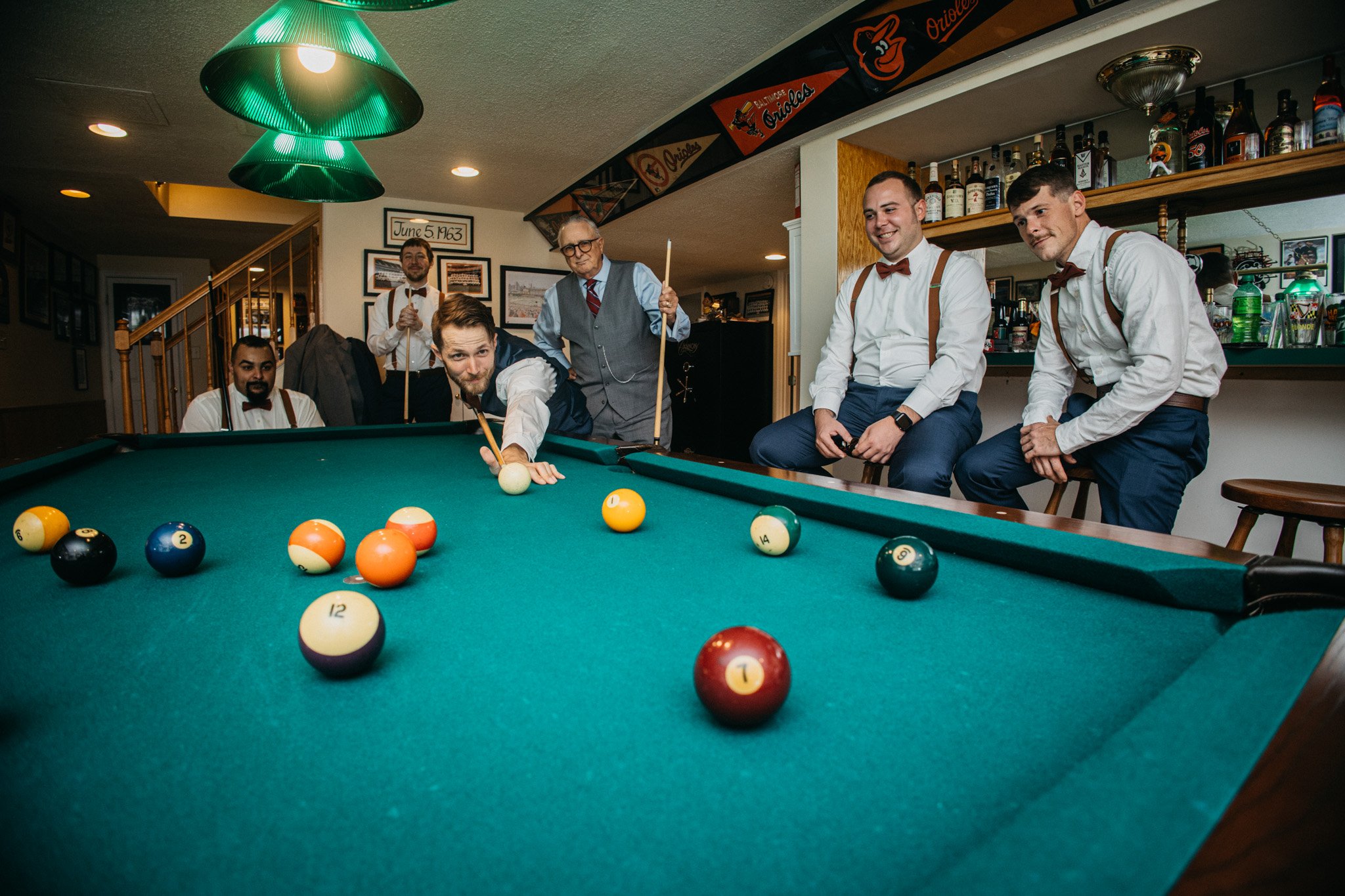 A bunch of groomsmen playing pool together. 