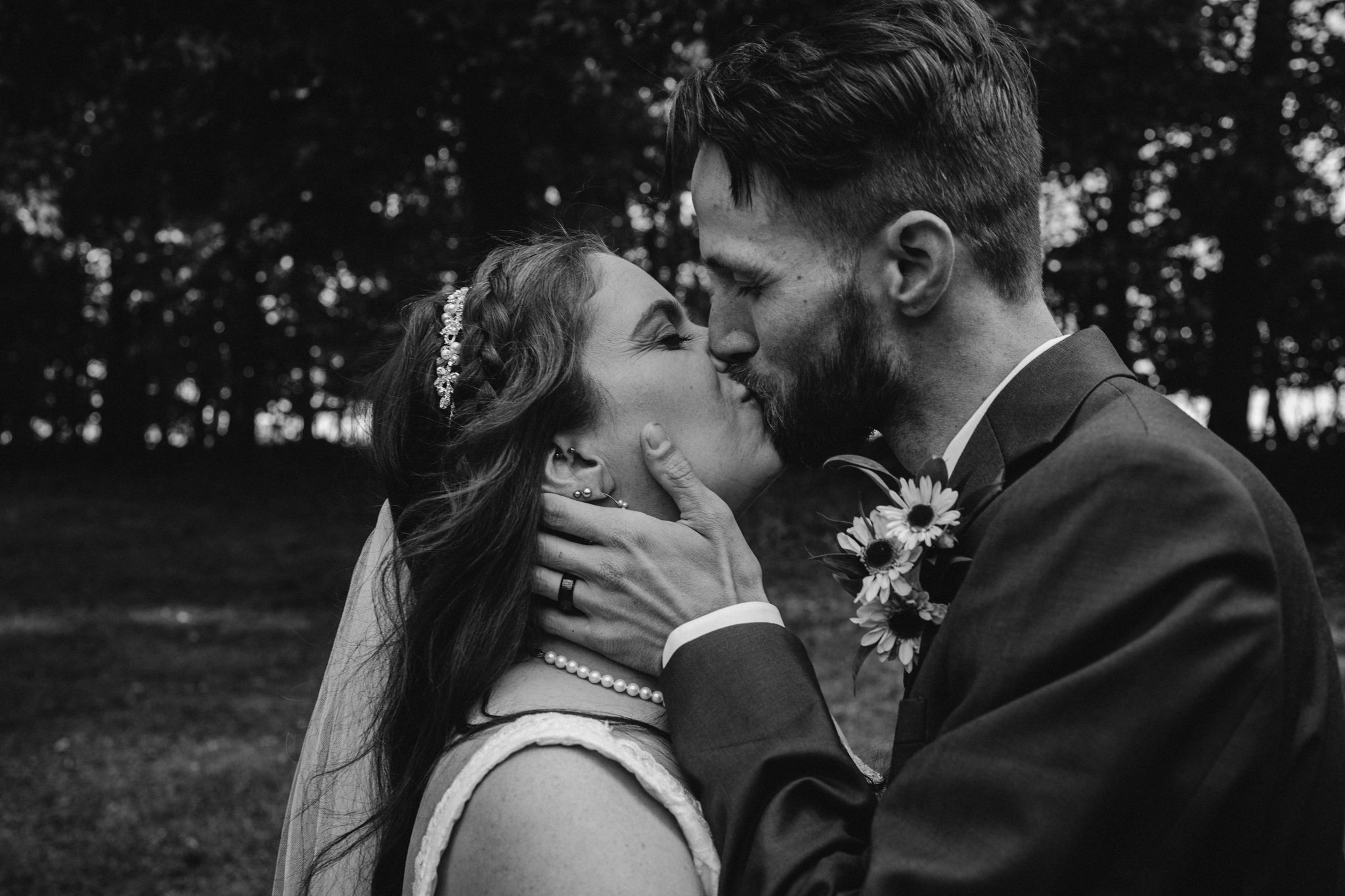 A bride and groom kiss, in black and white.