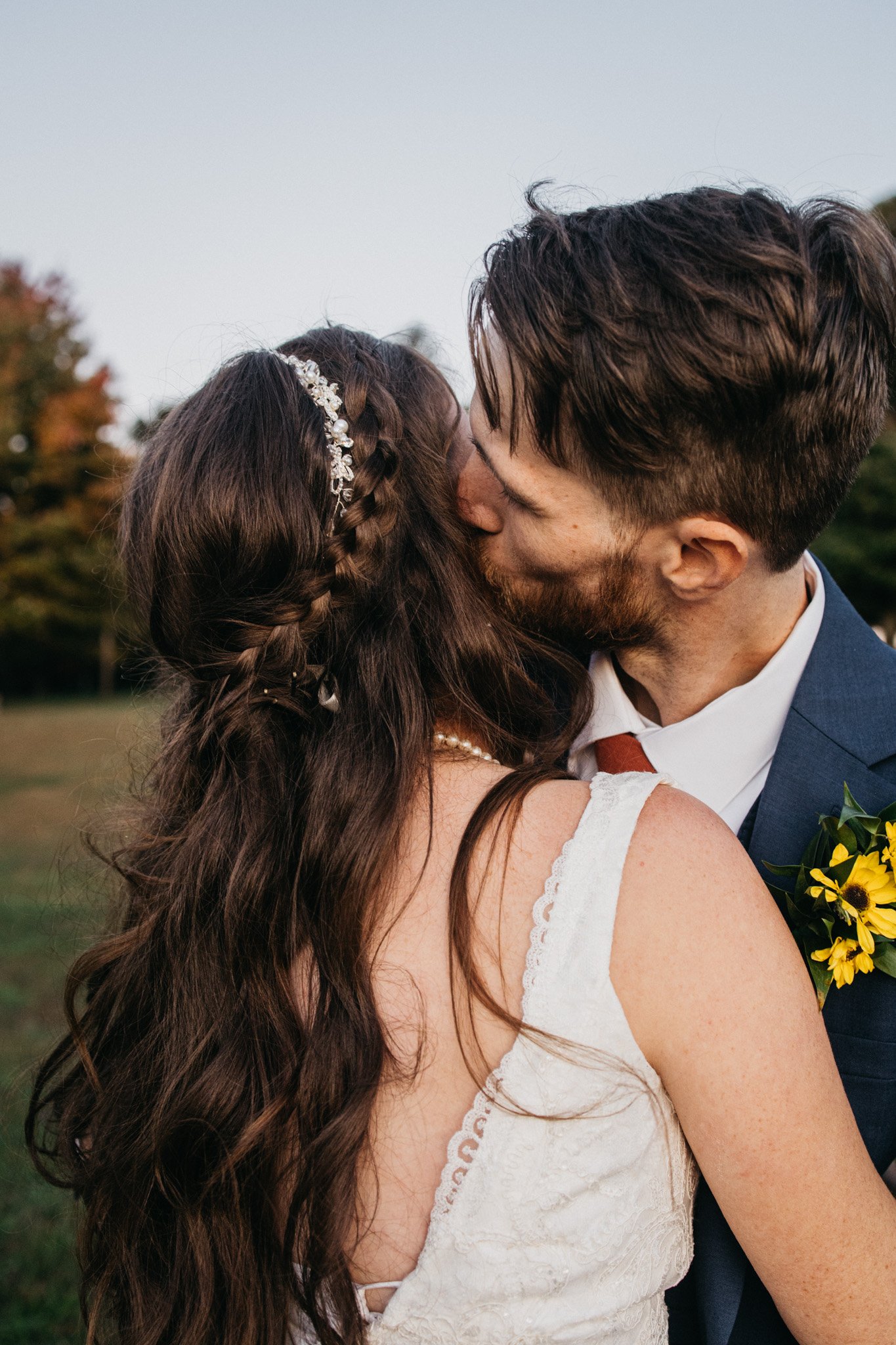 A groom kisses the side of the brides head.