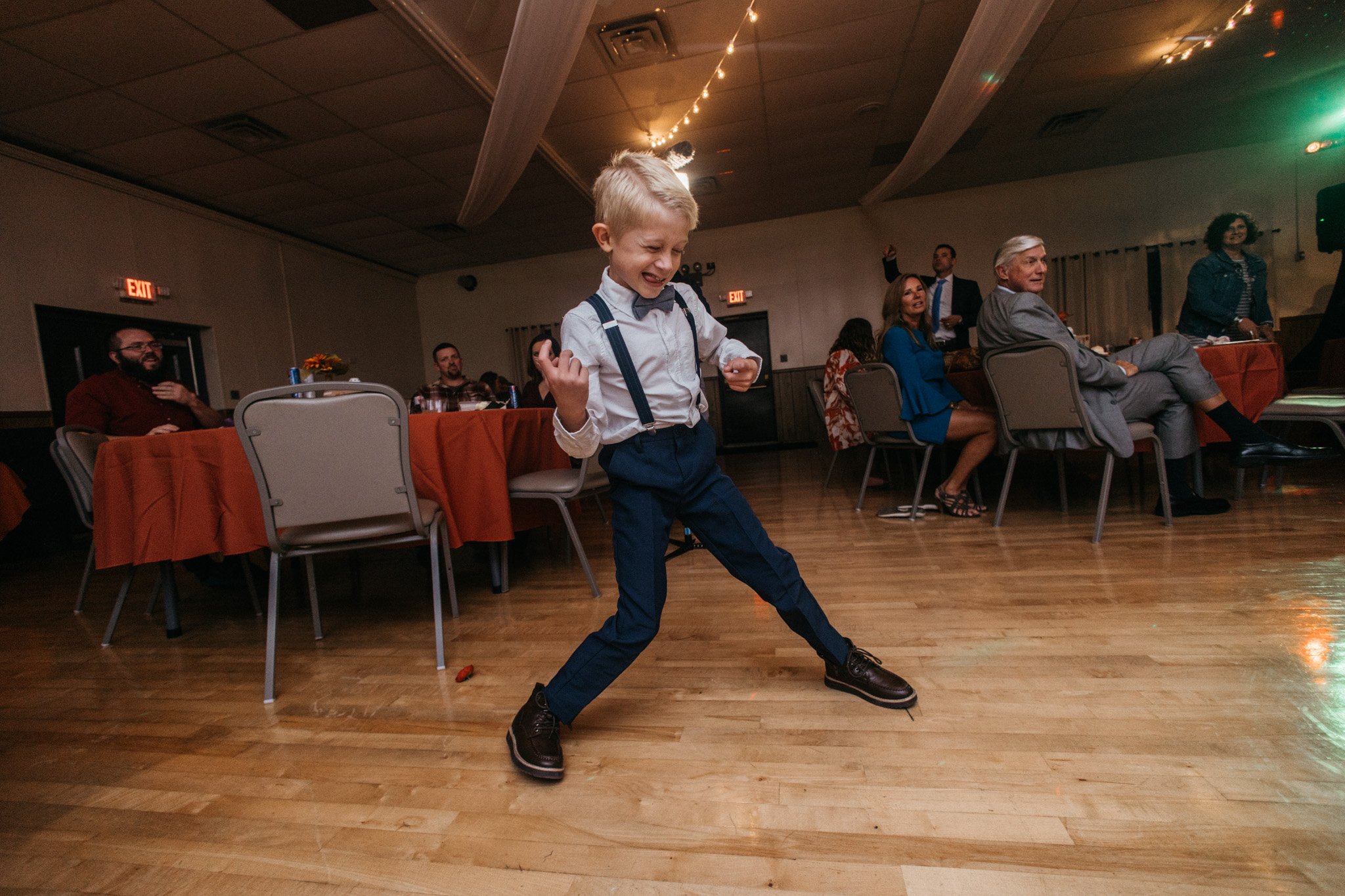 A wedding guest plays air guitar at a reception.