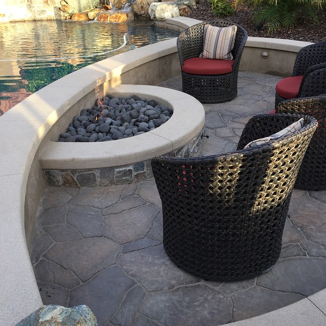 Sunken fire pit with natural rock waterfall.