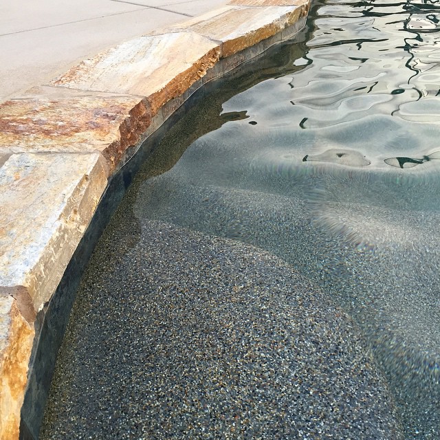 Sunset gold flagstone coping with pebble pool floor finish.