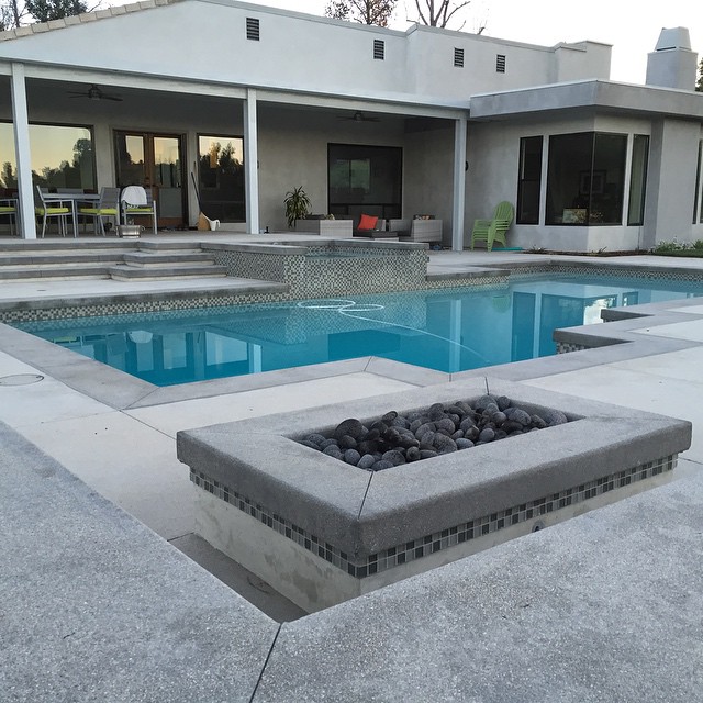 Tumbled lava rock in a modern mix of gray tones. Pewter gray cantilever concrete with Outback gray topcast concrete decking. Mid tone gray plaster pool.