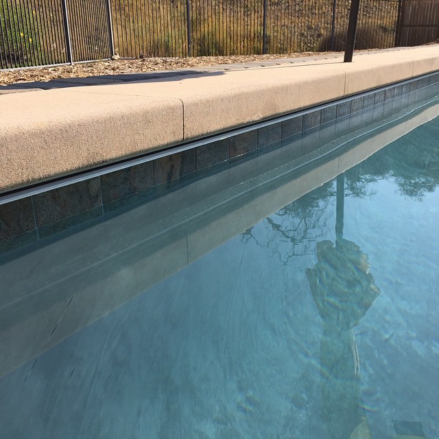 Automatic pool cover track system under cantilever concrete. Gray plaster