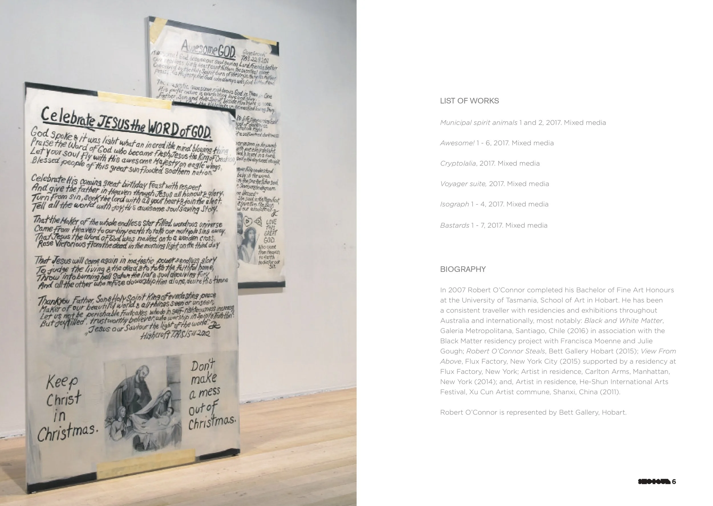 An art exhibit display featuring handwritten notes and drawings related to Christmas and Jesus Christ, with a white wall and wooden floor background.