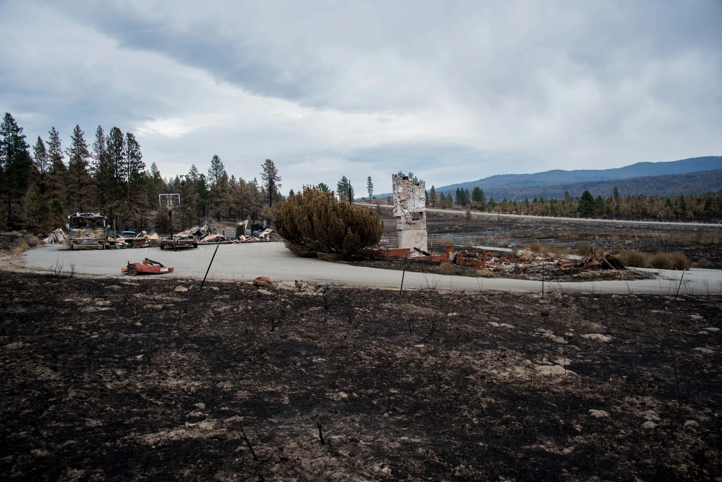 Burnt evidence of where a home once stood before the wildfires this summer in Washington. All that remains is the shell of an RV, a basket ball hoop and part of the chimney.