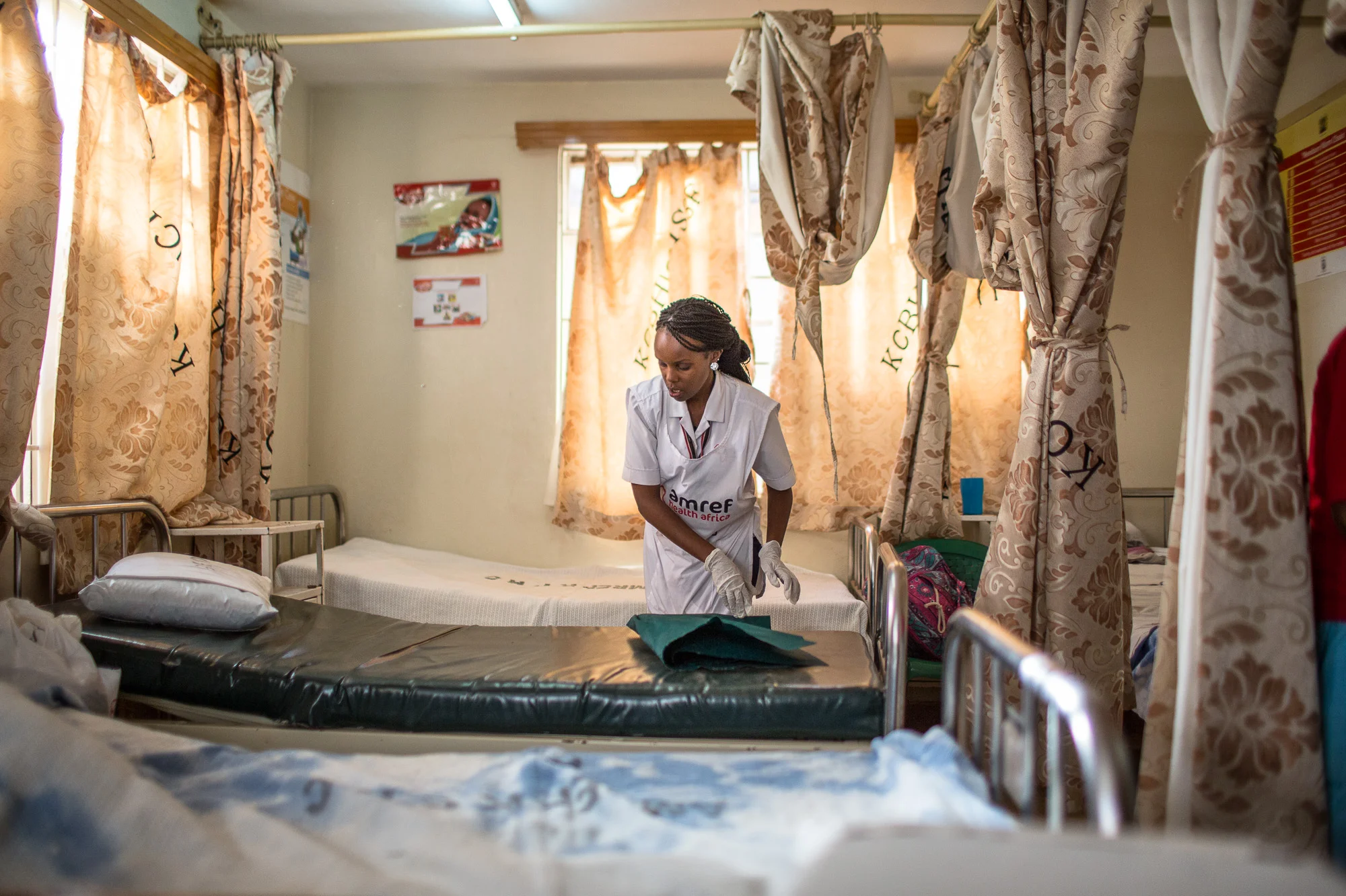 Lydia, a nurse but also head of facility at Kibera AMREF centre makes a bed in the maternity ward. AMREF provides training for hundreds of community health workers to help pregnant women, babies and those living with HIV to be healthy and safe.