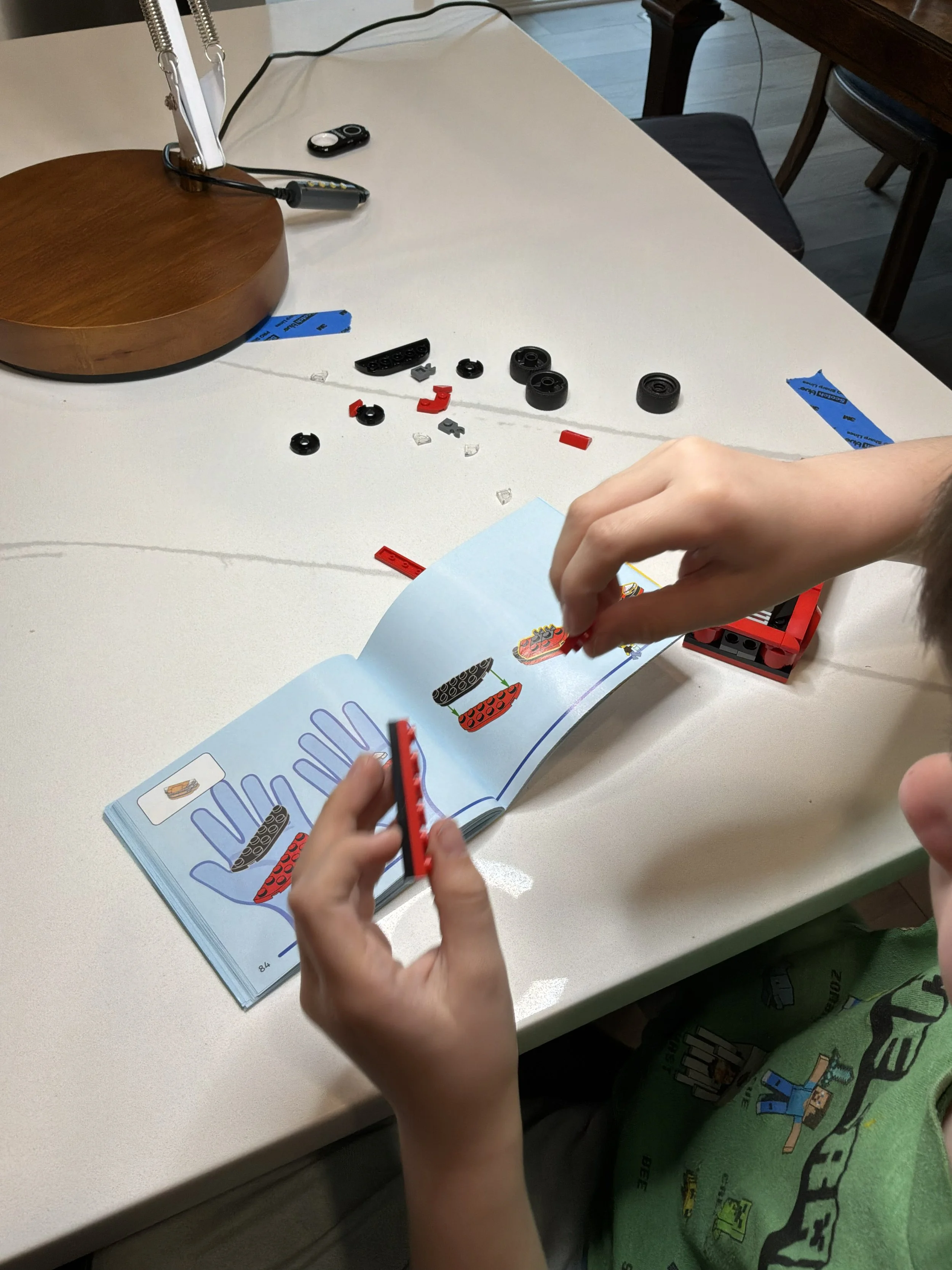 small hands carefully assembling toy car pieces using illustrated instructions