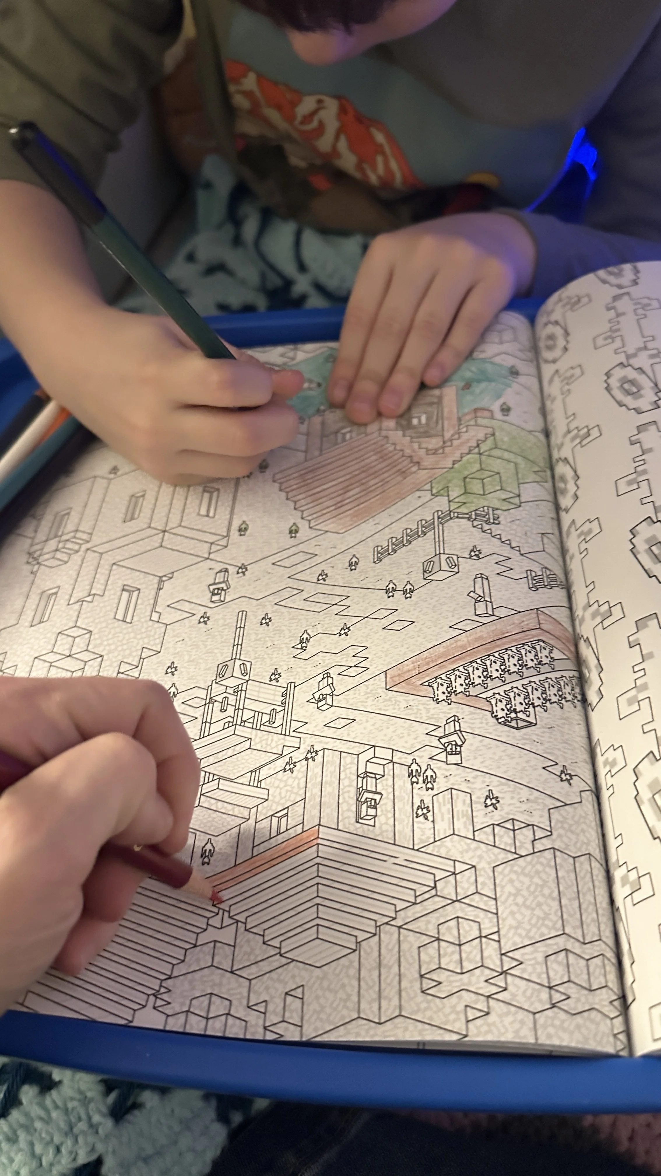 Child coloring Minecraft coloring book at table with colored pencils