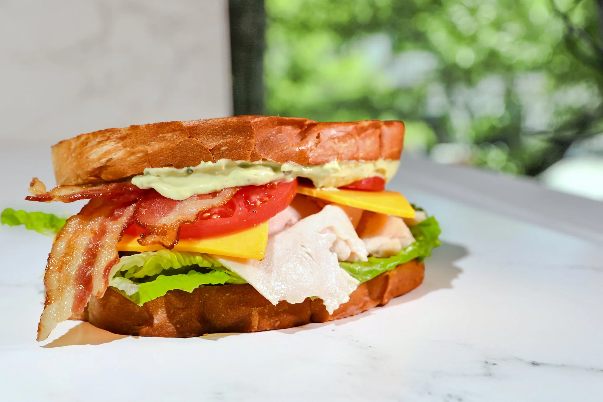 Commercial food photography of a turkey club sandwich with bacon, lettuce, tomato, and toasted bread for Best Buns Bakery & Burgers.