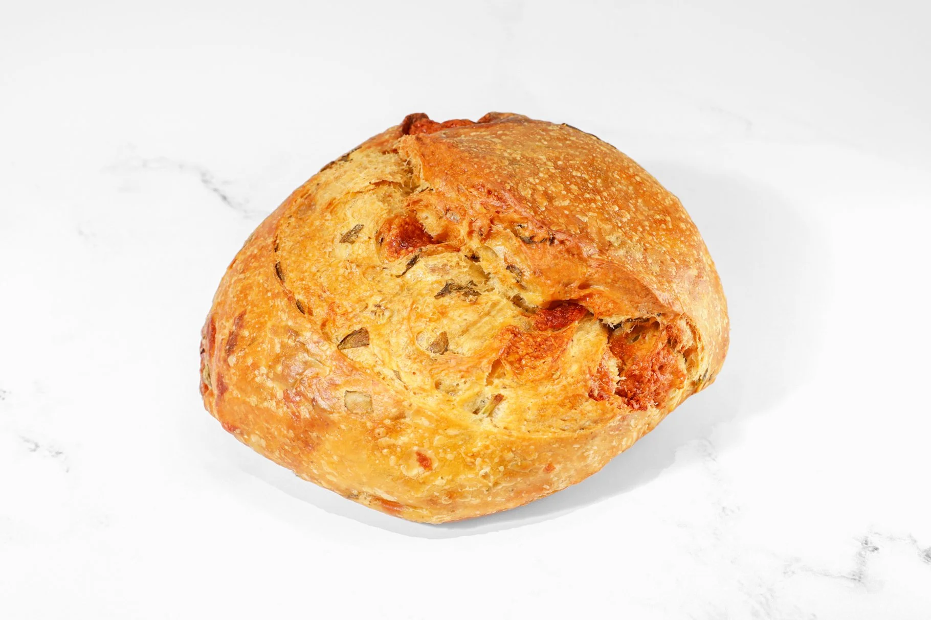 Product photography of a freshly baked artisan sourdough bread loaf for a bakery menu and marketing.