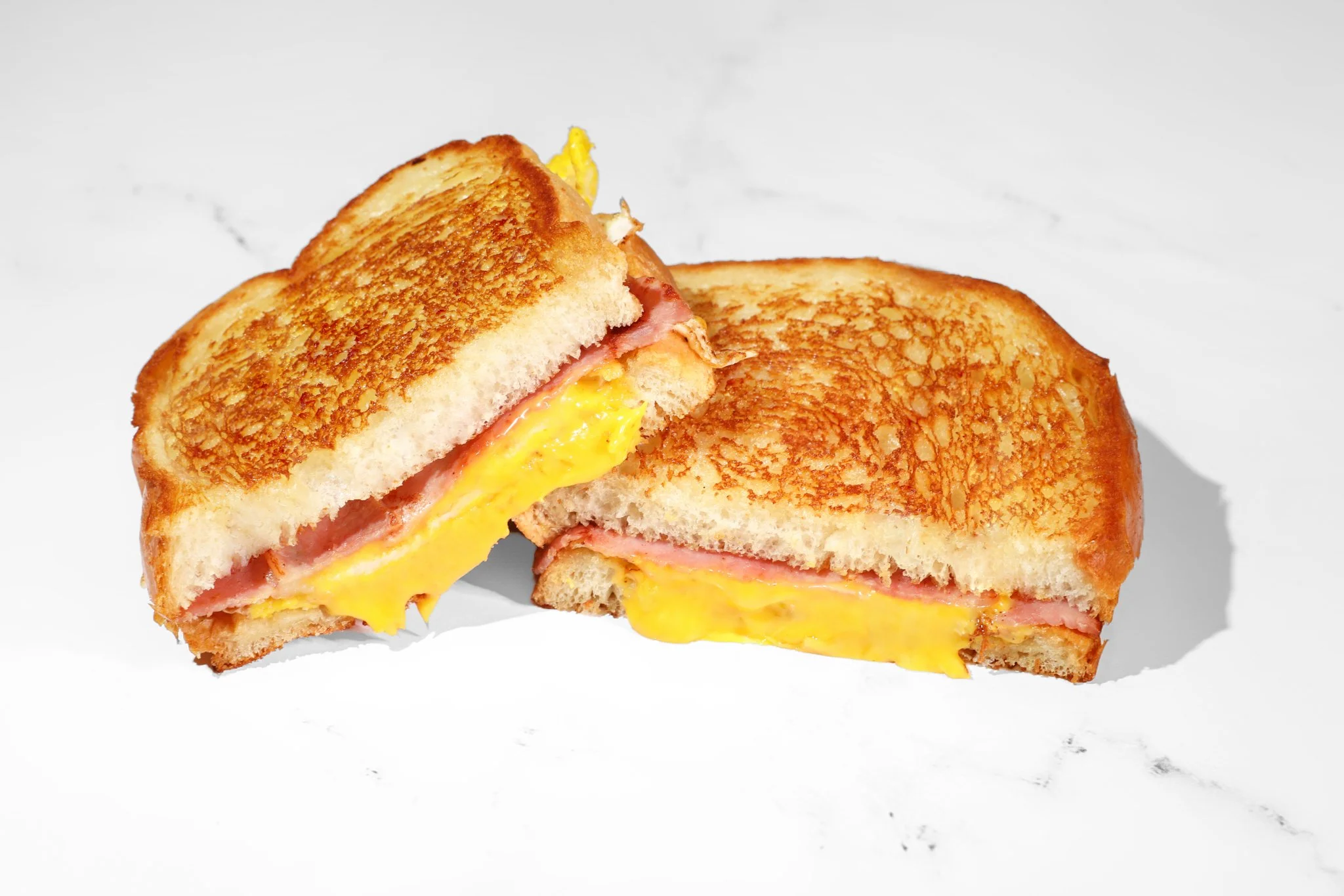 Food photography of a classic ham and cheese sandwich on artisan bread for restaurant marketing.