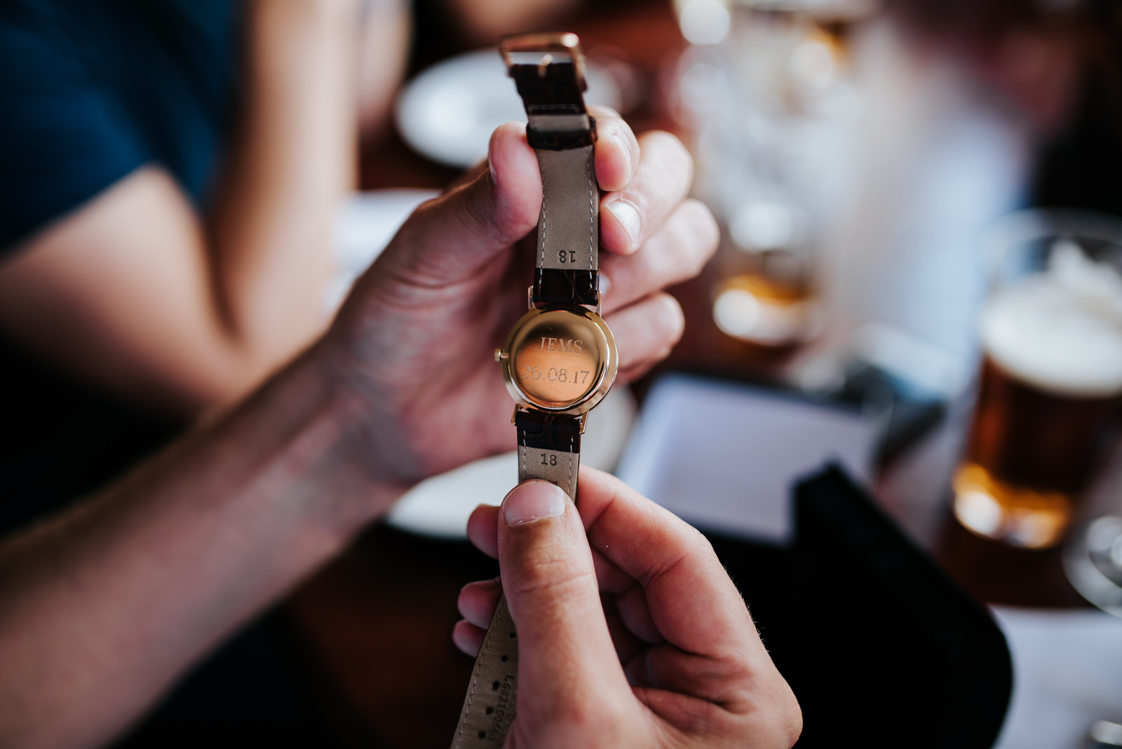 Groom looks at monogrammed watch bride gifted him