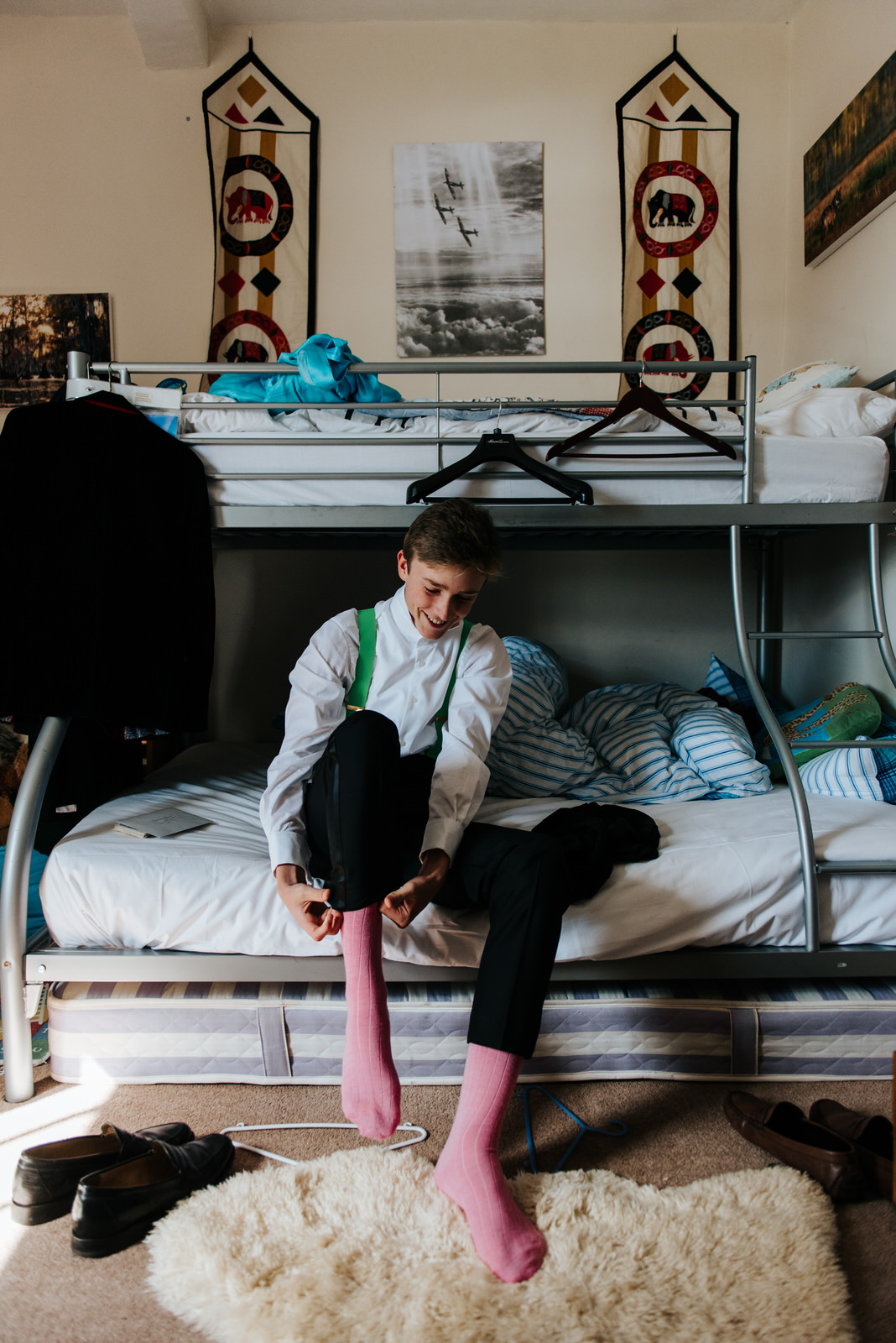 Bride's brother smiling as he puts on socks before wedding