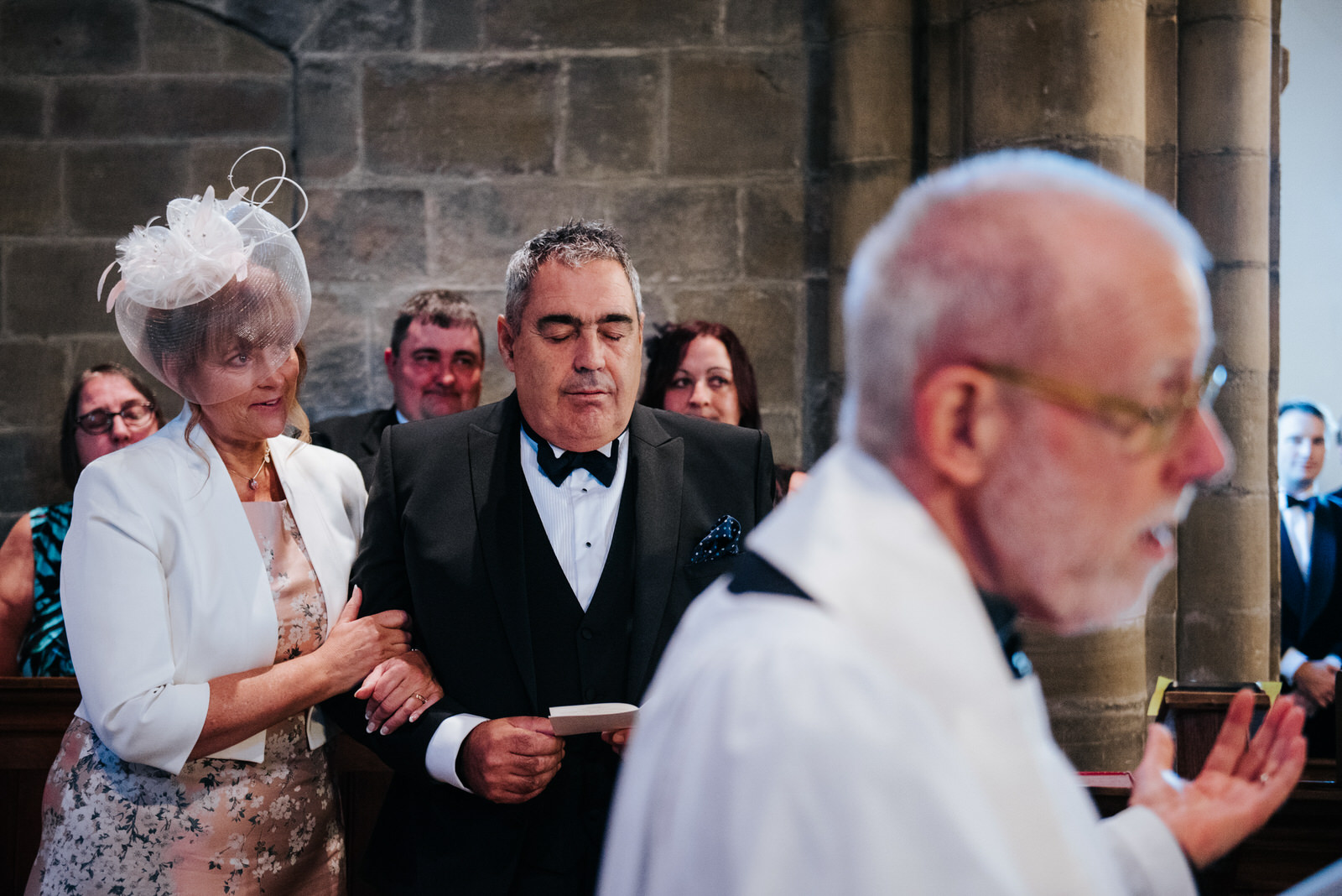 Father of the Groom closes eyes and embraces his wife as the wed