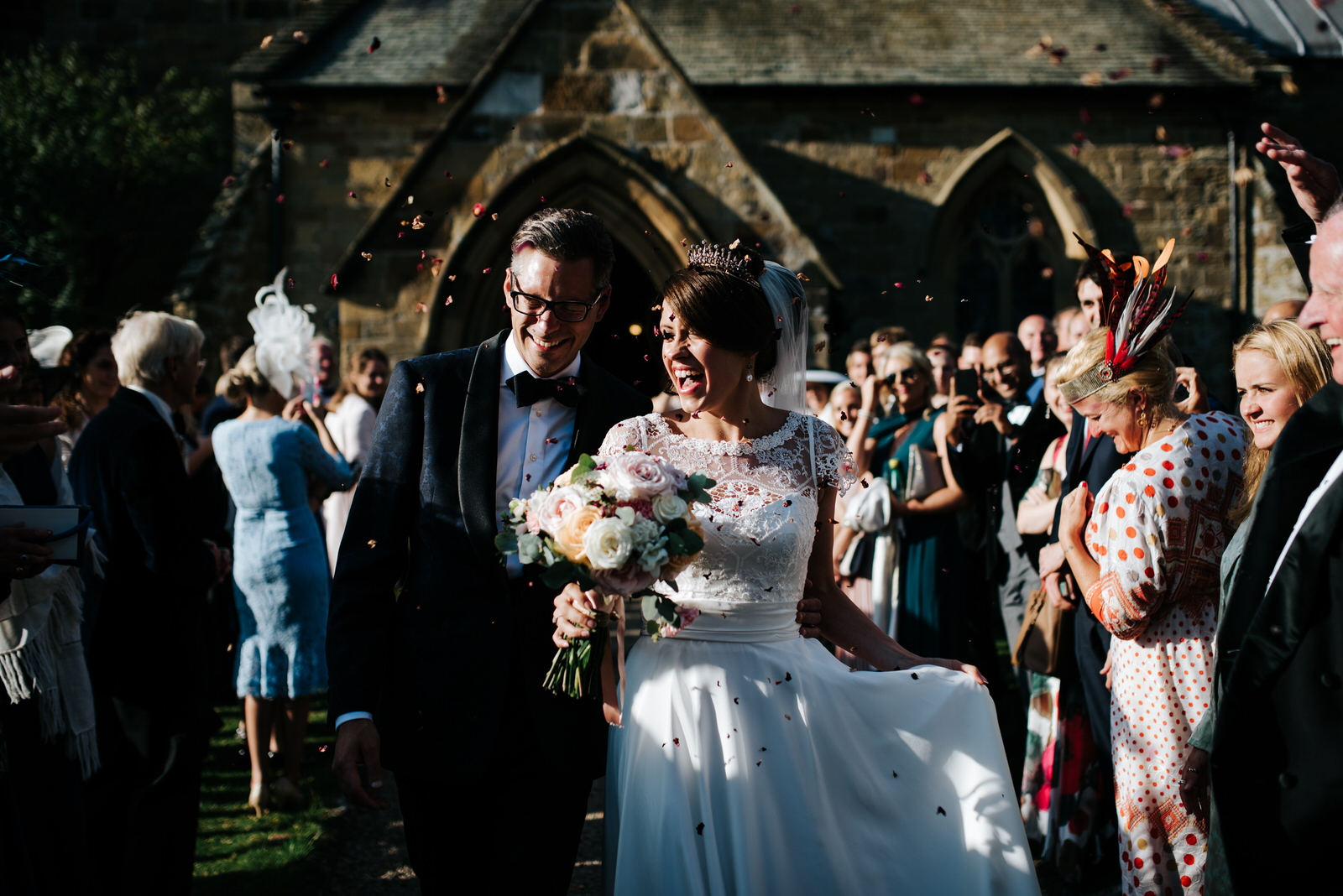 Bride and Groom walk through tunnel of guests while having confe