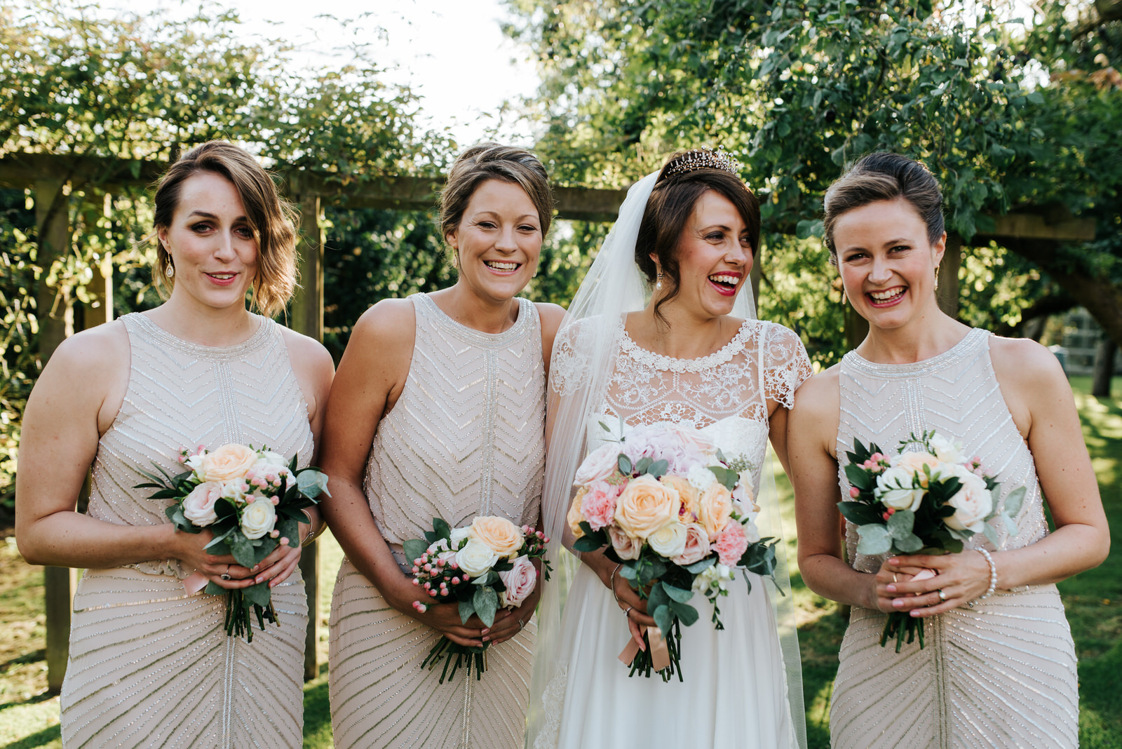 Bride and Bridesmaids smile at camera in stunning garden