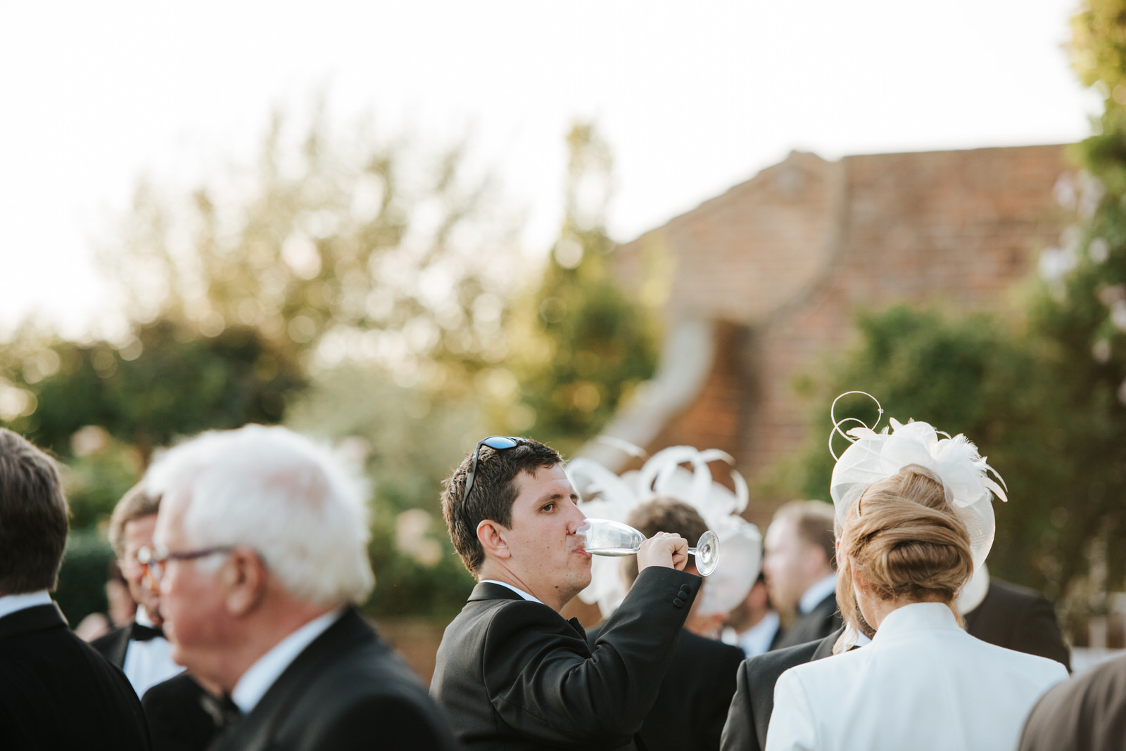 Groom's best man drinks champagne in beautiful, green garden wed