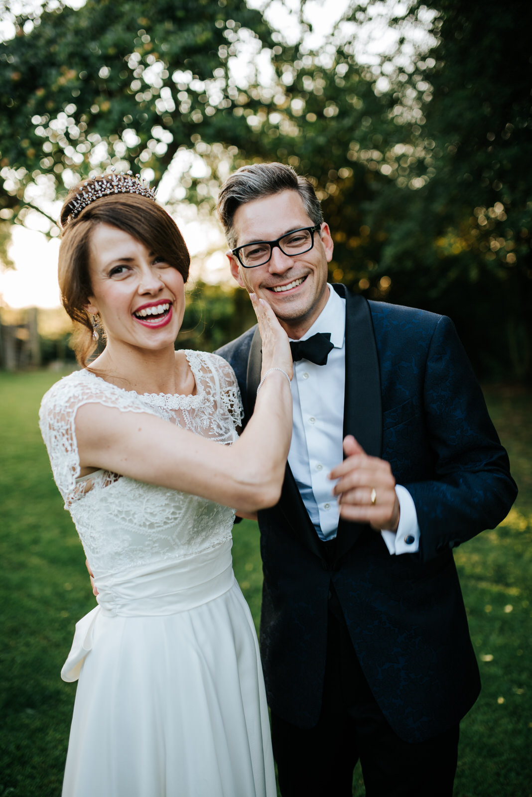 Bride rubs lipstick off Groom in orchard next to wedding recepti