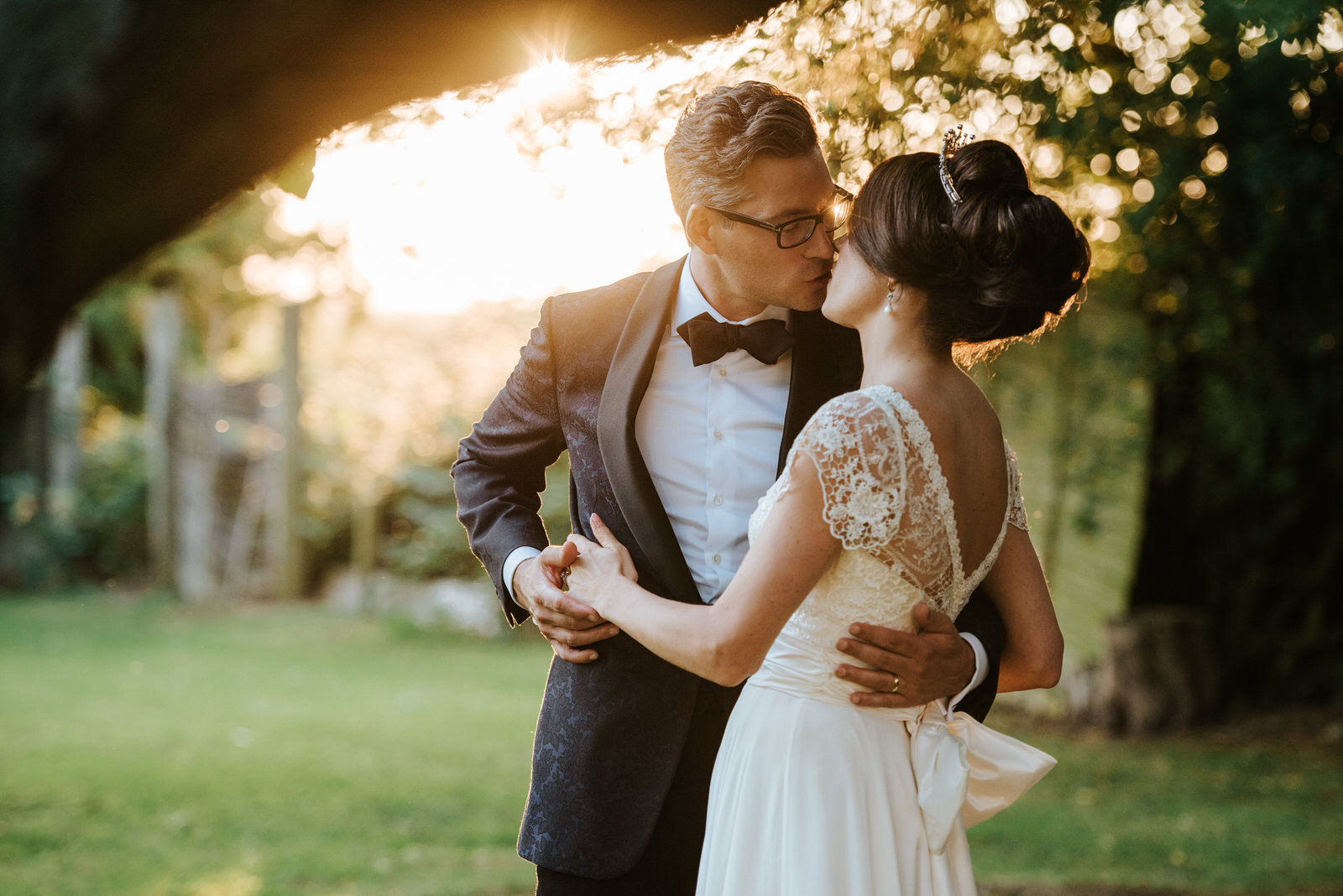 Bride and Groom romantic photo as they kiss under the setting su