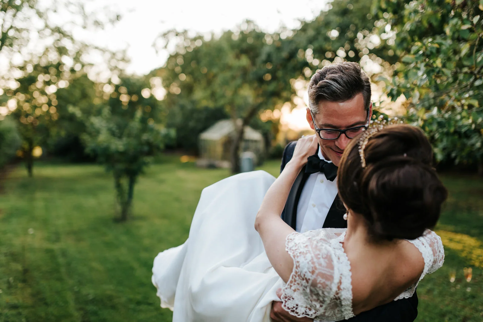 Groom dips bride while she grabs onto his neck during sunset pho