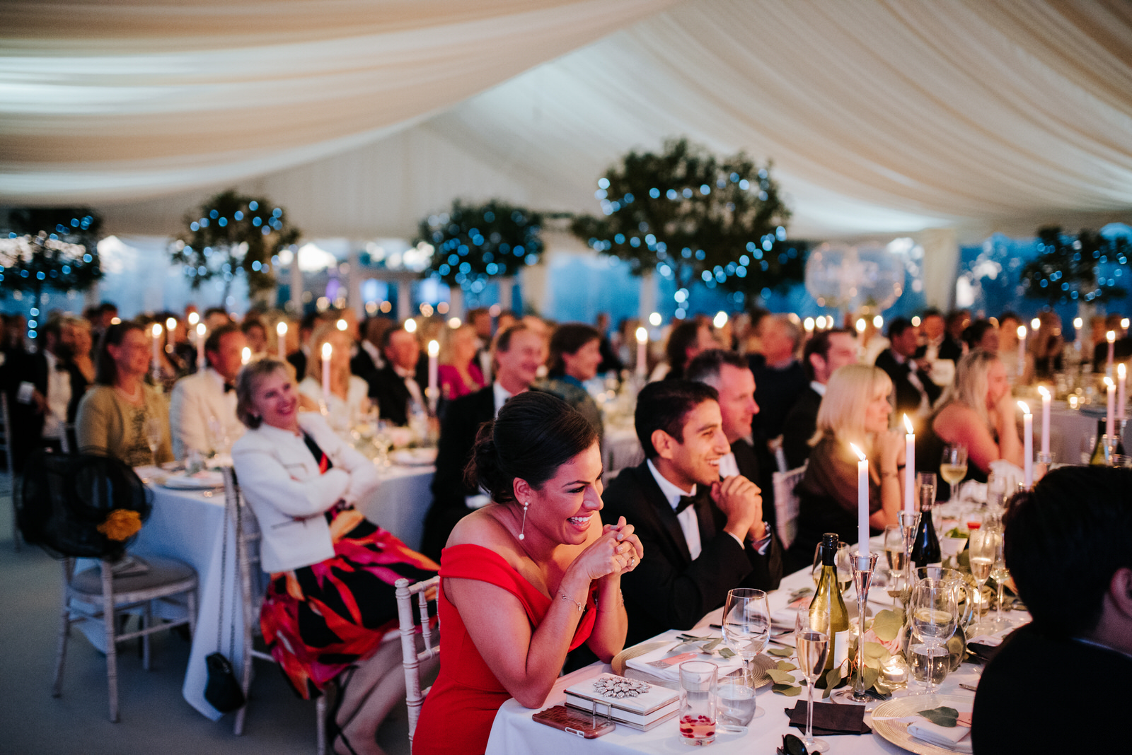 Guests are amused as speeches are delivered in candle-lit marque