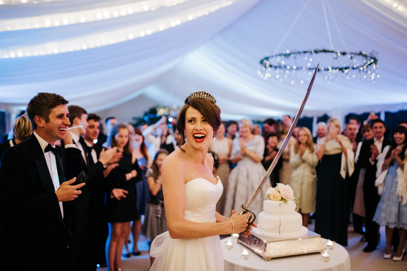 Bride holds military sword after cutting wedding cake as guests 