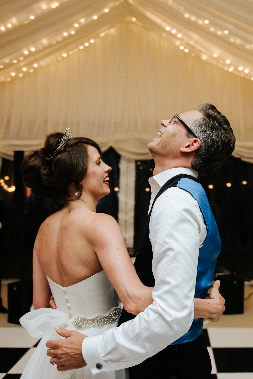 Bride and groom smile and laugh as first dance inside garden mar