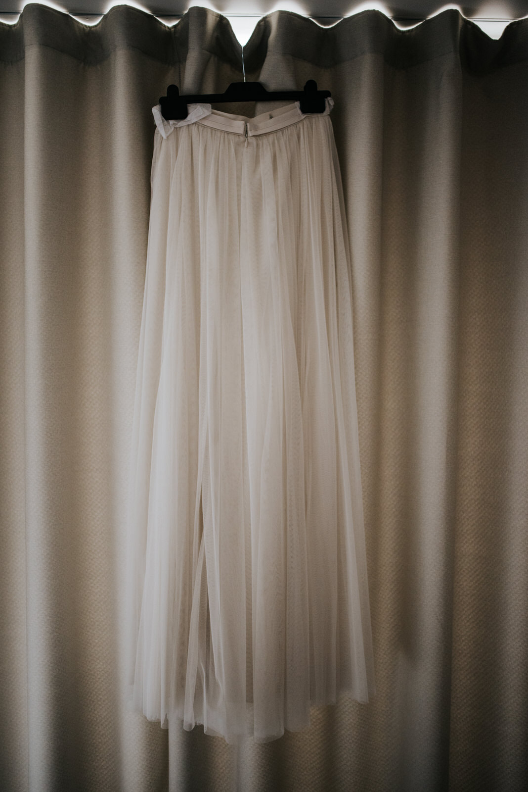 Bride's wedding skirt hanging by the window