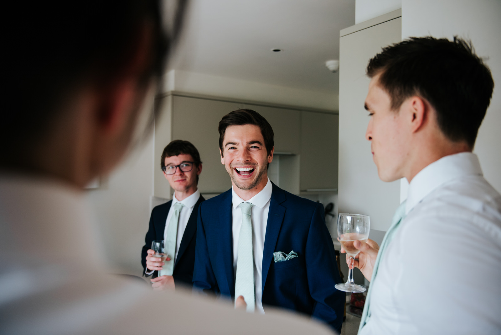 Groom and groomsmen laugh while sharing emotional advice before 