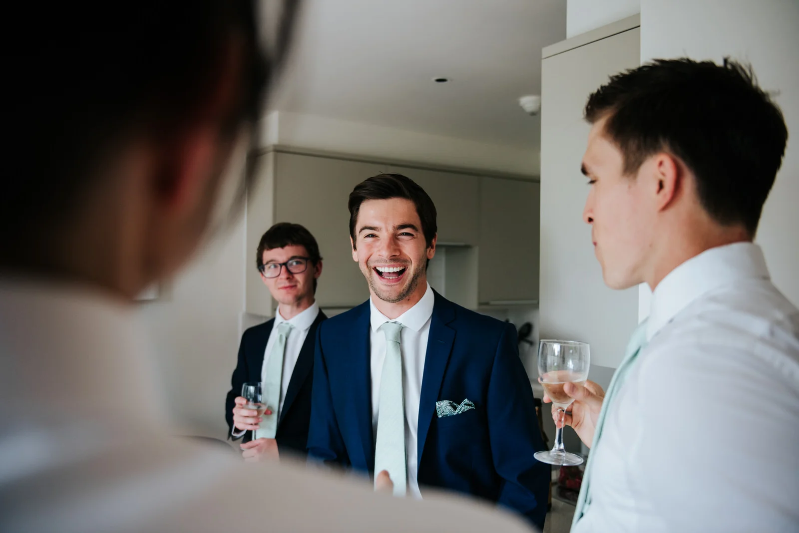 Groom and groomsmen laugh while sharing emotional advice before