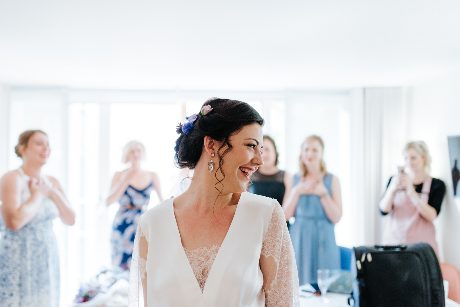 Bride twirls and smiles in her dress in front of bridesmaids