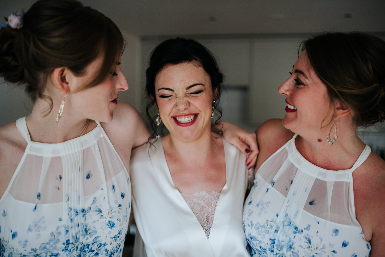 Bride and her sisters laugh and smile before leaving for wedding