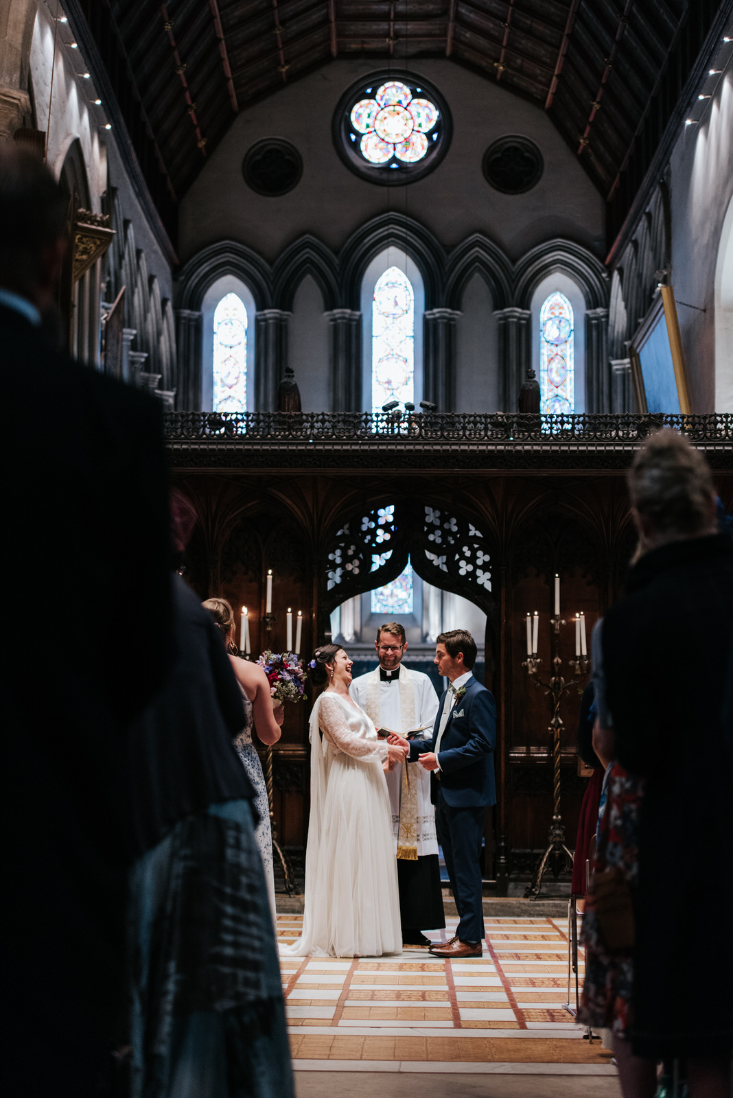 Bride and Groom hold hands and laugh out loud as vicar pronounce