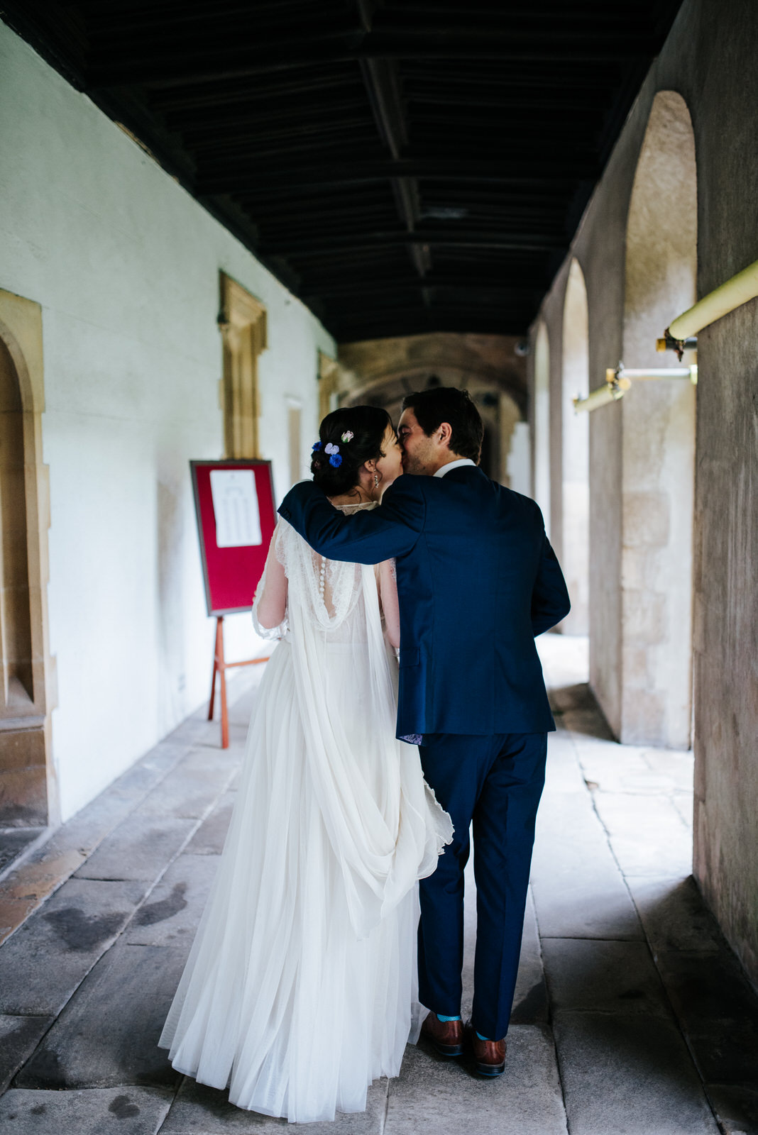Bride and groom exit Jesus College Chapel and kiss as they are n