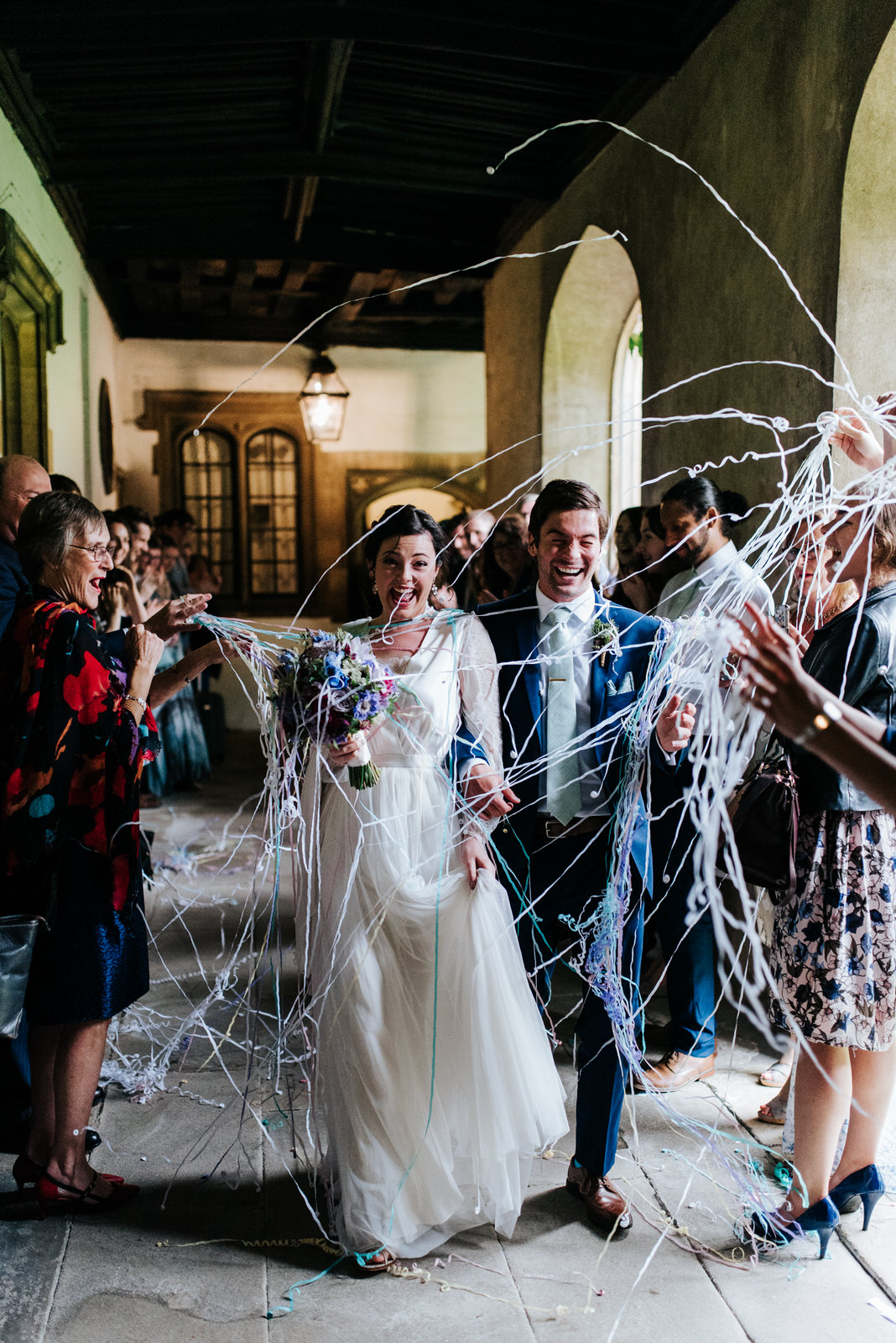 Bride and groom walk down a tunnel of guests as confetti is thro