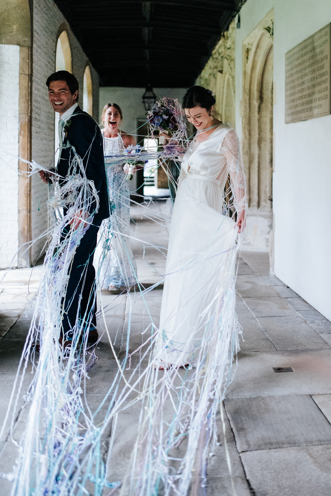 Bride and groom completely covered in strings of confetti as the