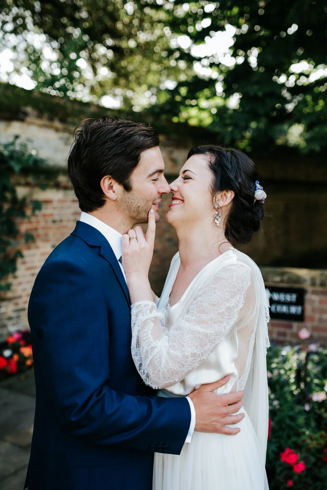 Bride and groom rub noses romantically under beautiful trees