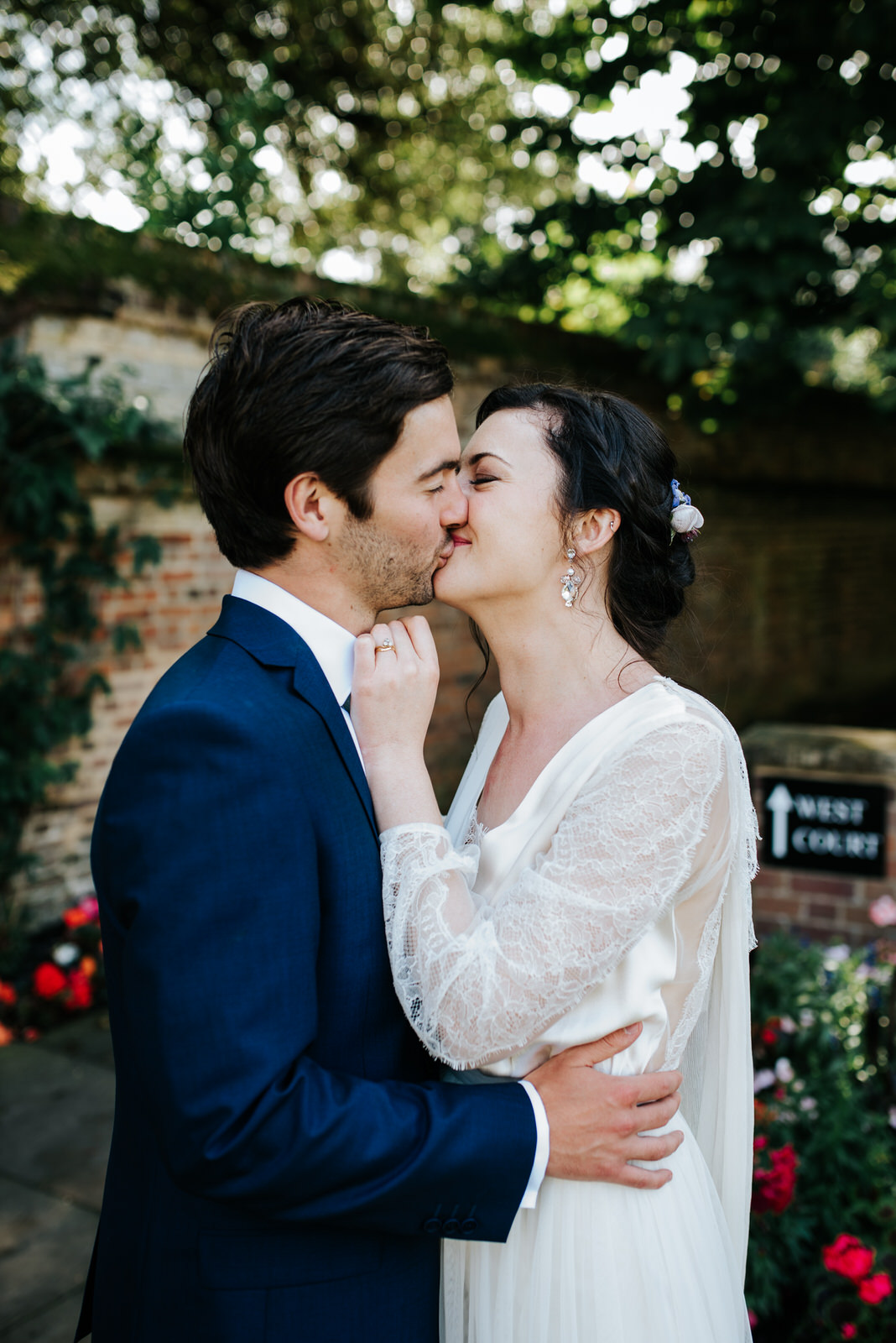 Bride and groom kiss under beautiful green trees during couple p