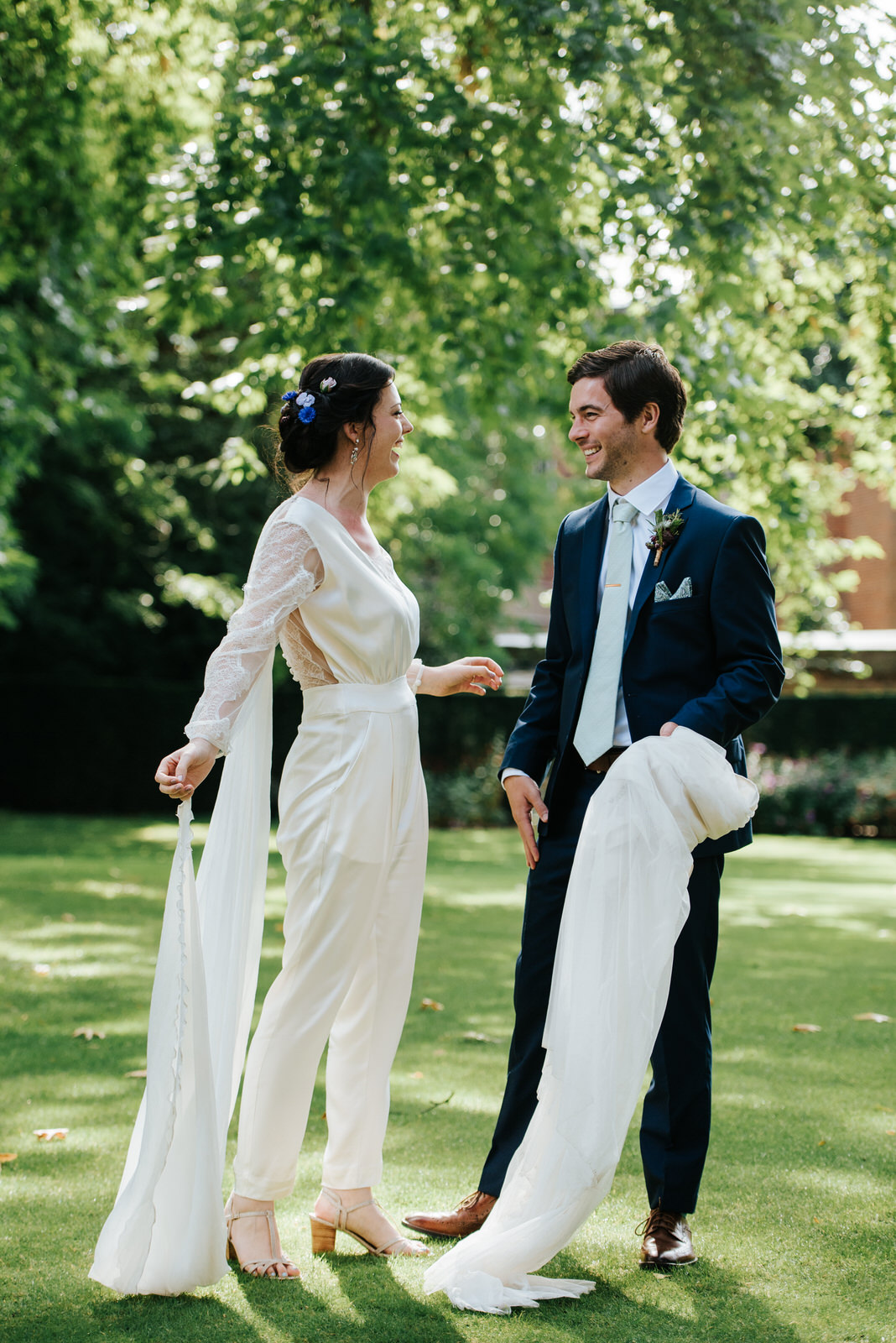 Groom smiles at bride as he holds the wedding skirt she has just