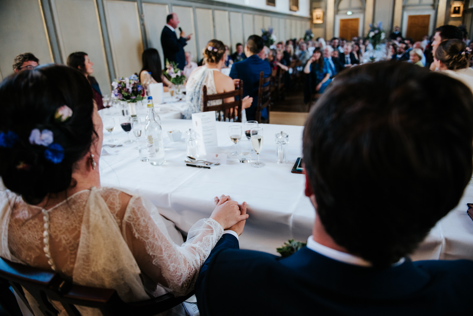Bride and groom hold hands under the table in romantic moment du