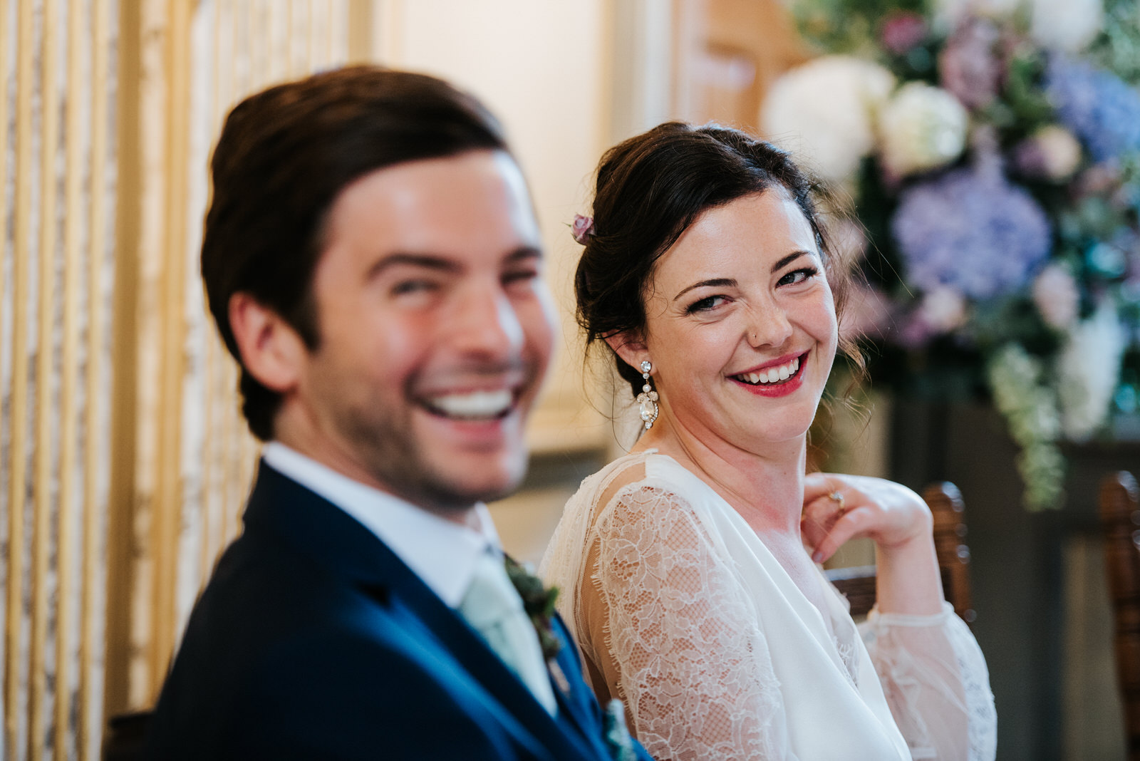 Groom and bride smile with teeth and look into camera