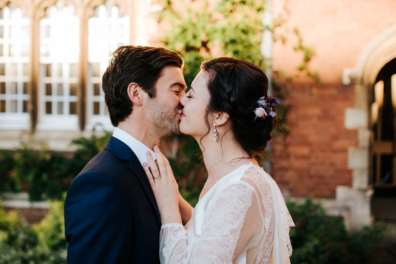 Bride and groom kiss and embrace in Jesus College Chapel Court