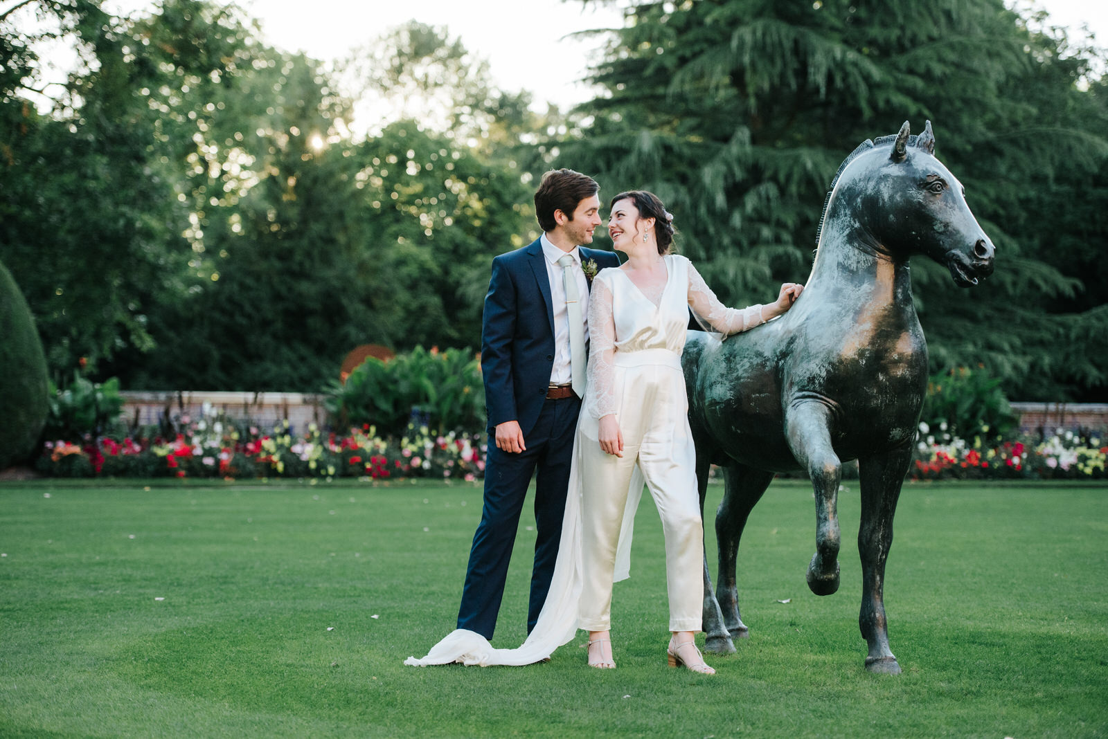 Bride and groom look at each other while posing with Jesus Colle