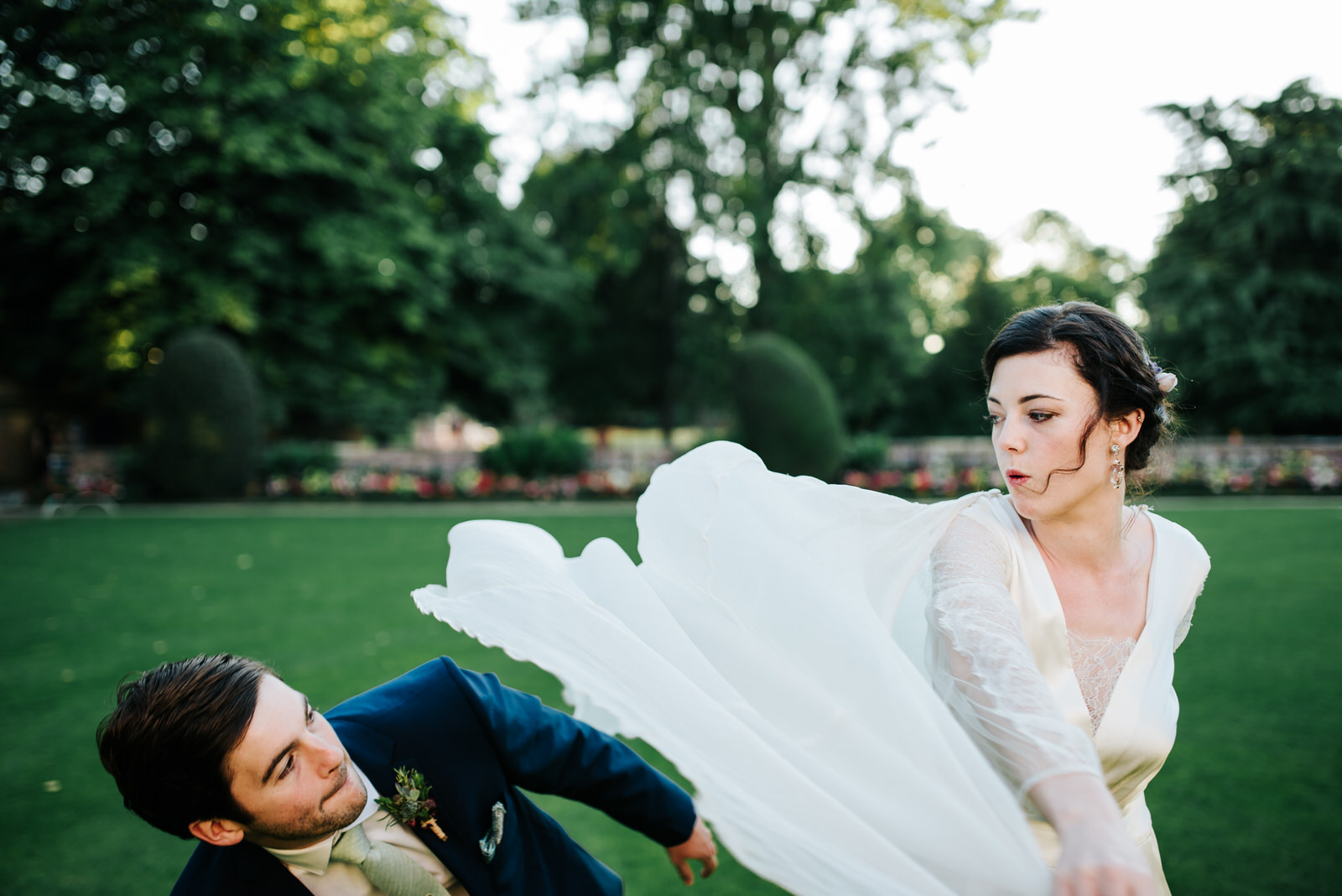 Bride swings her dress at groom pretending it is a superhero cap